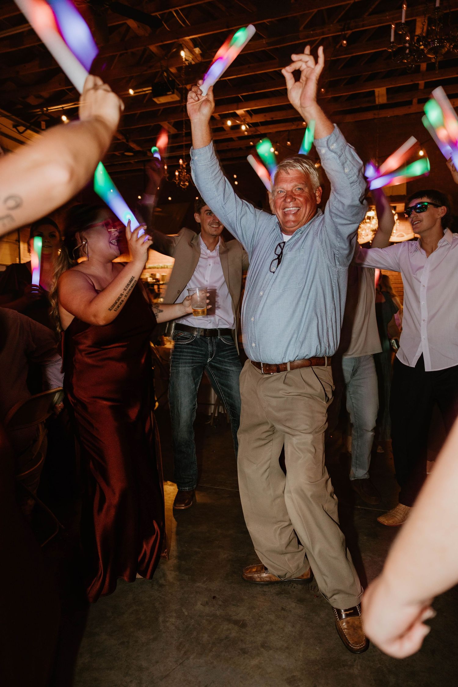 Party guests dancing with glowing light sticks at a festive indoor celebration.