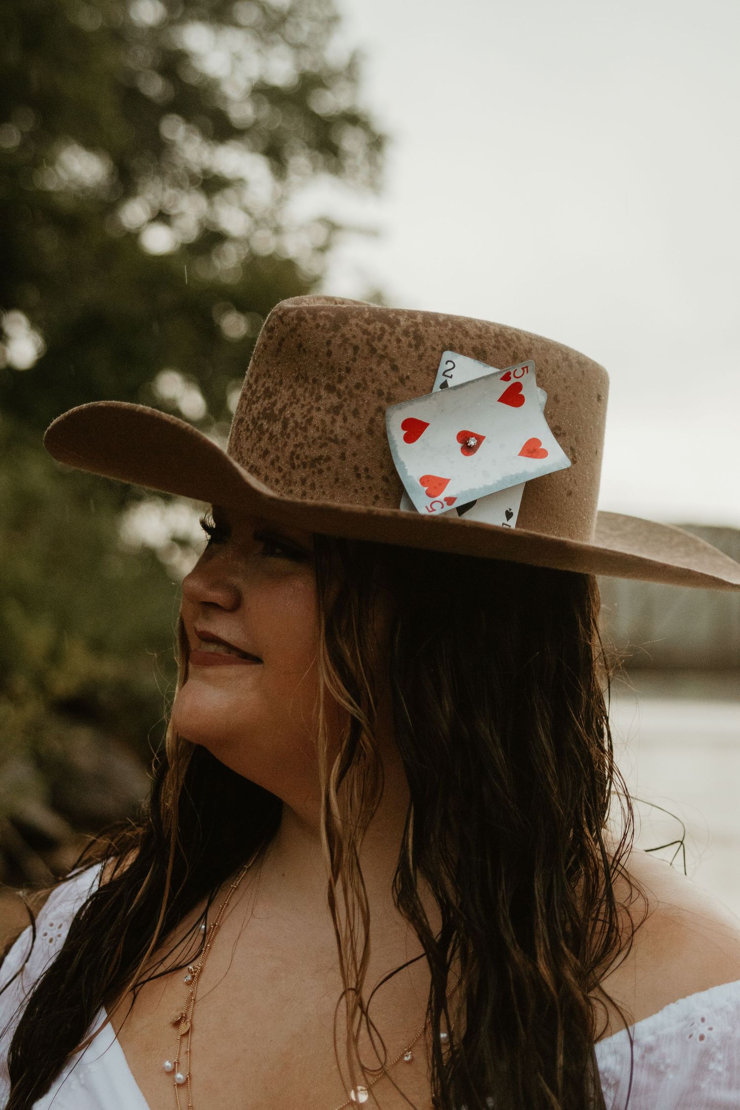 Brown hat with playing cards adorns person during lakeside photoshoot at sunset near Lake Hartwell.