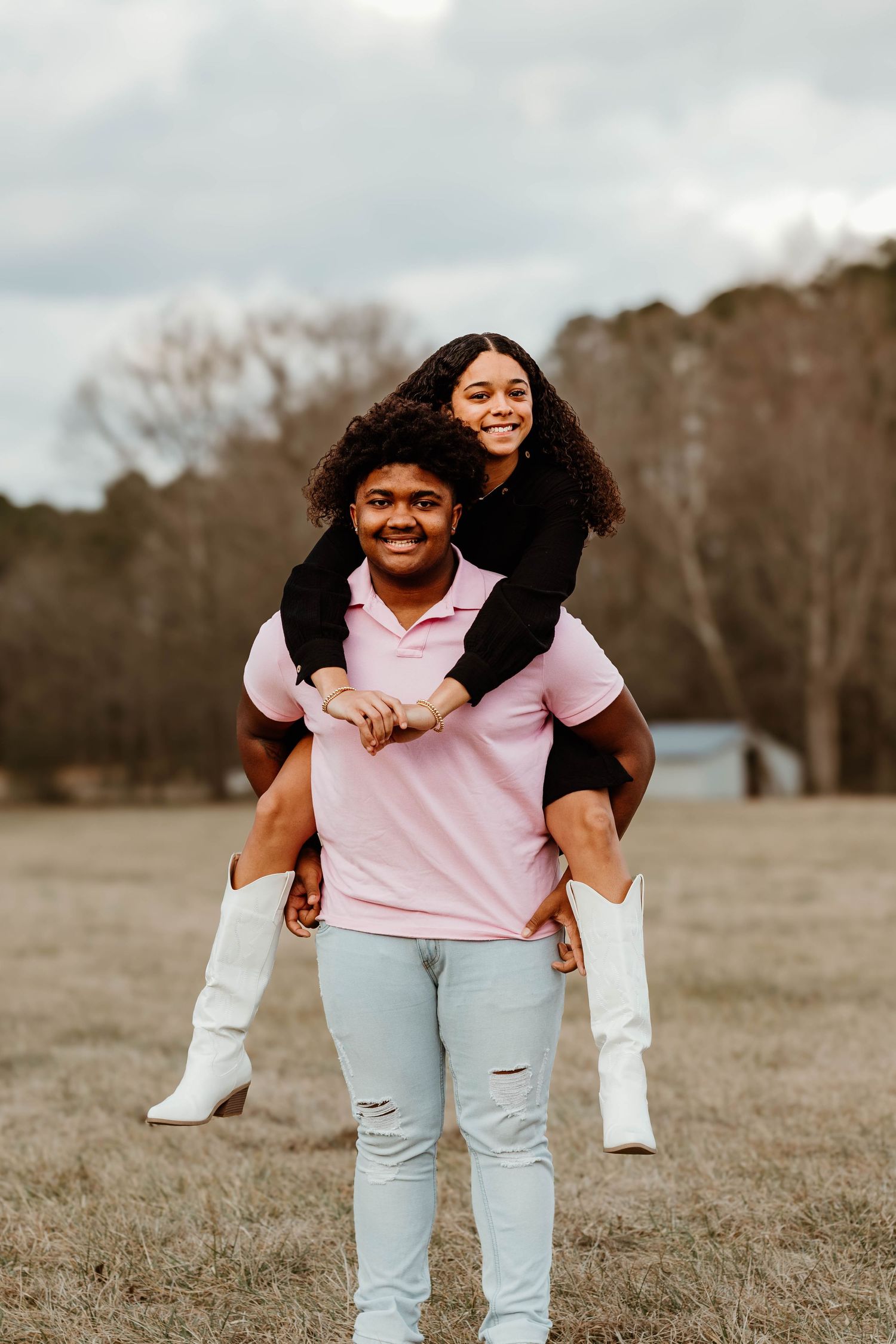 A playful piggyback ride in an open field between a couple wearing pink and black outfits at Geary Farm in northeast Georgia.