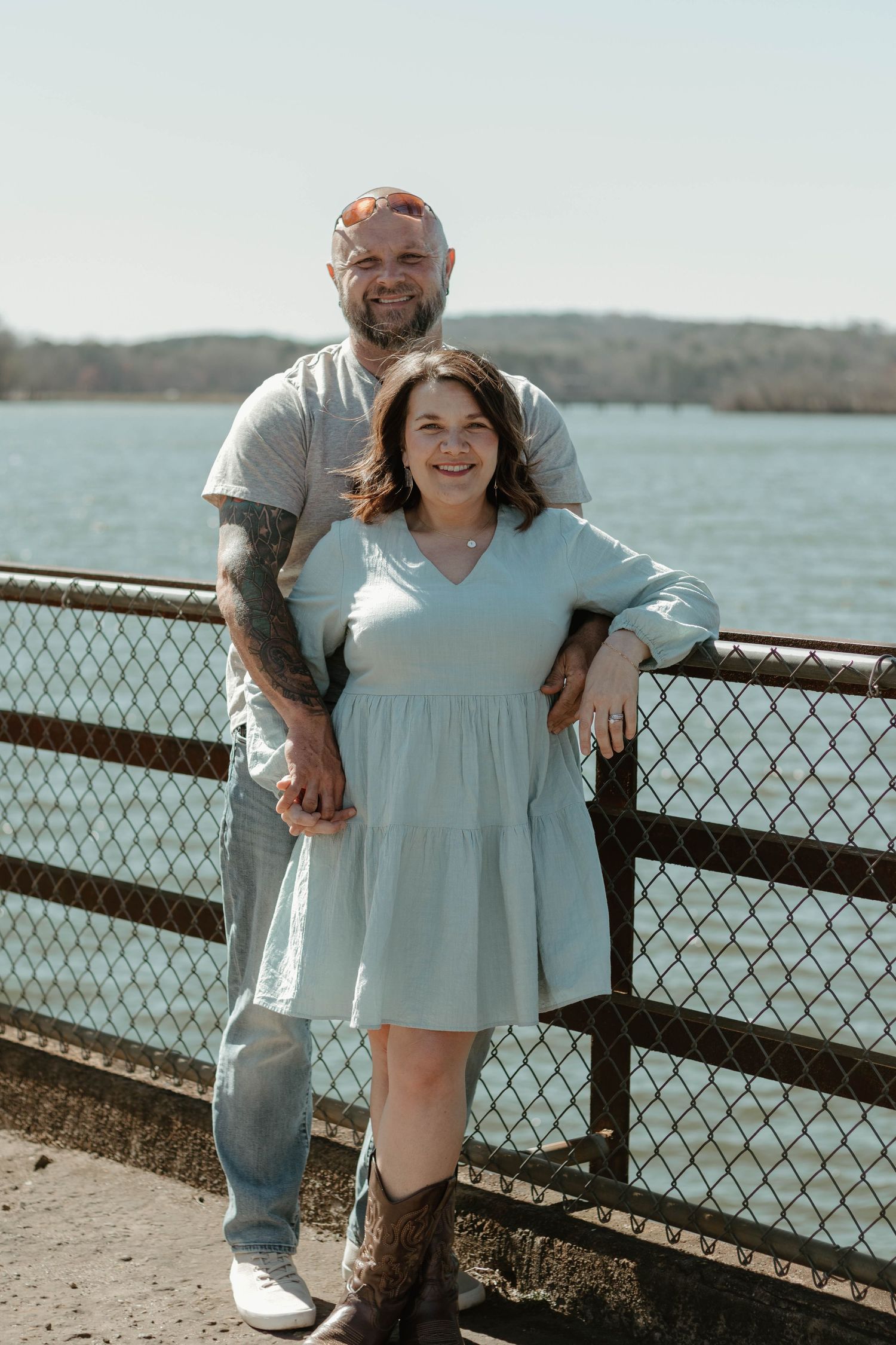A couple poses together on a waterfront boardwalk on a sunny day at Broken Bridges on Lake Hartwell.