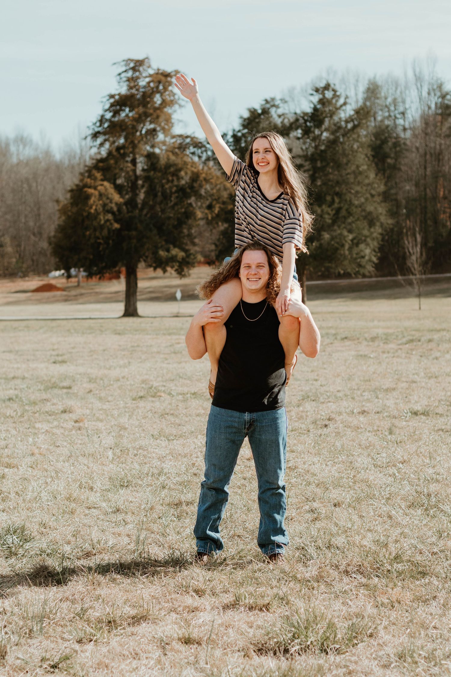Playful couple having fun with shoulder ride in open field in North Georgia.