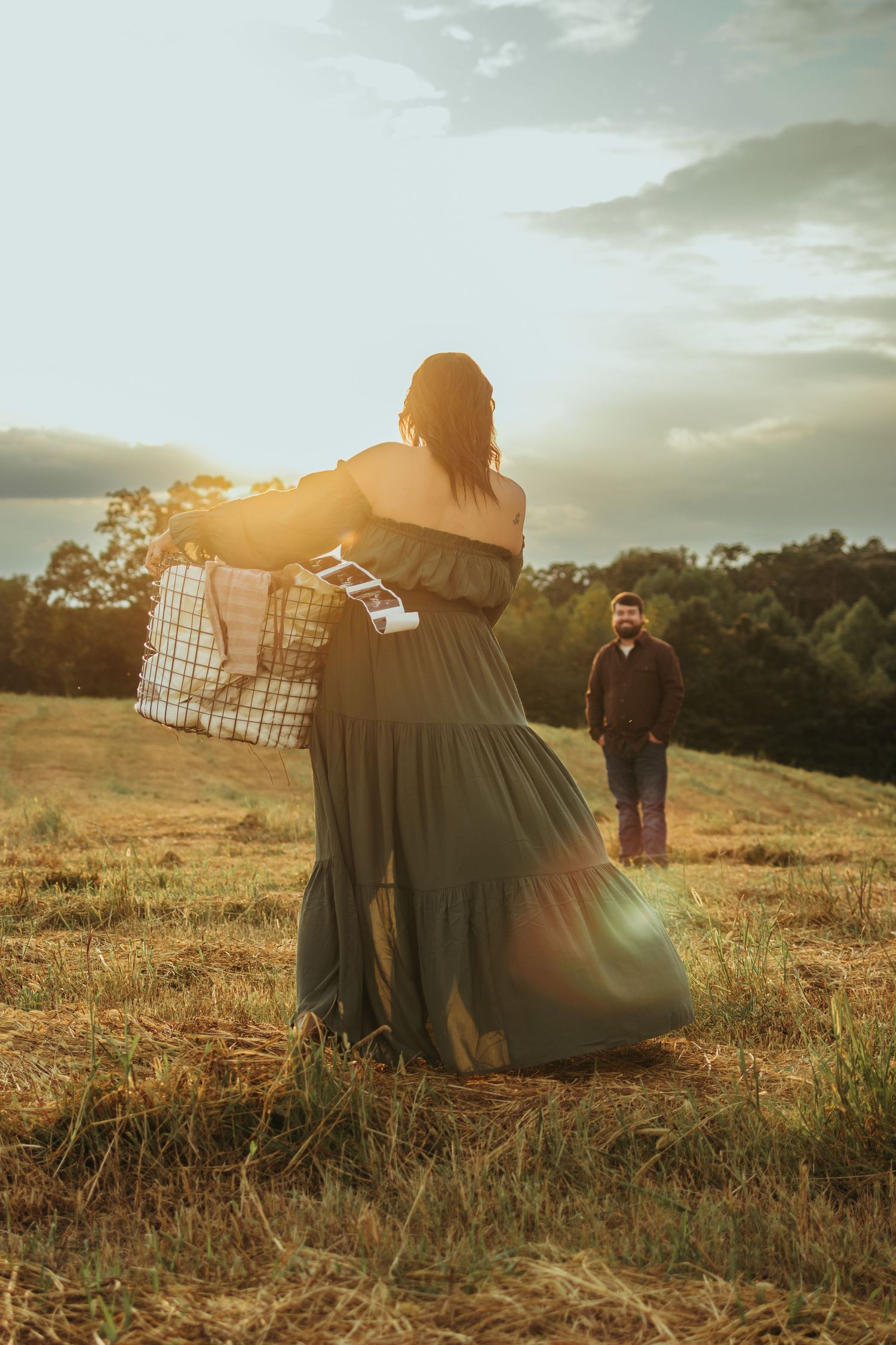 A couple shares an intimate moment in a sunlit field at golden hour for maternity photos in Toccoa, GA.