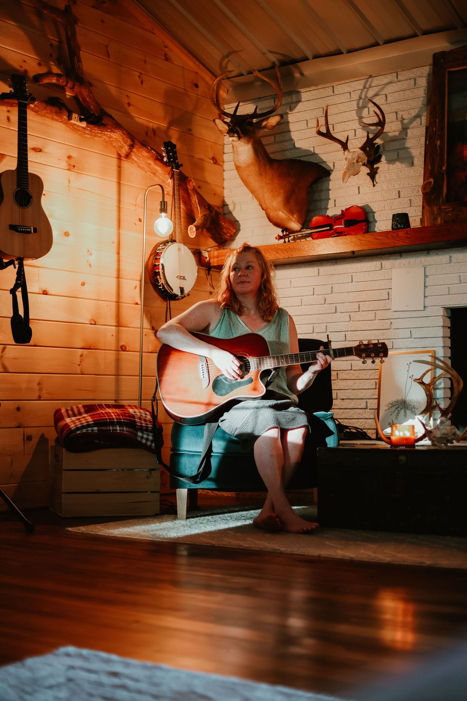 Musician performing in a cozy cabin room decorated with mounted antlers and instruments in northeast Georgia.