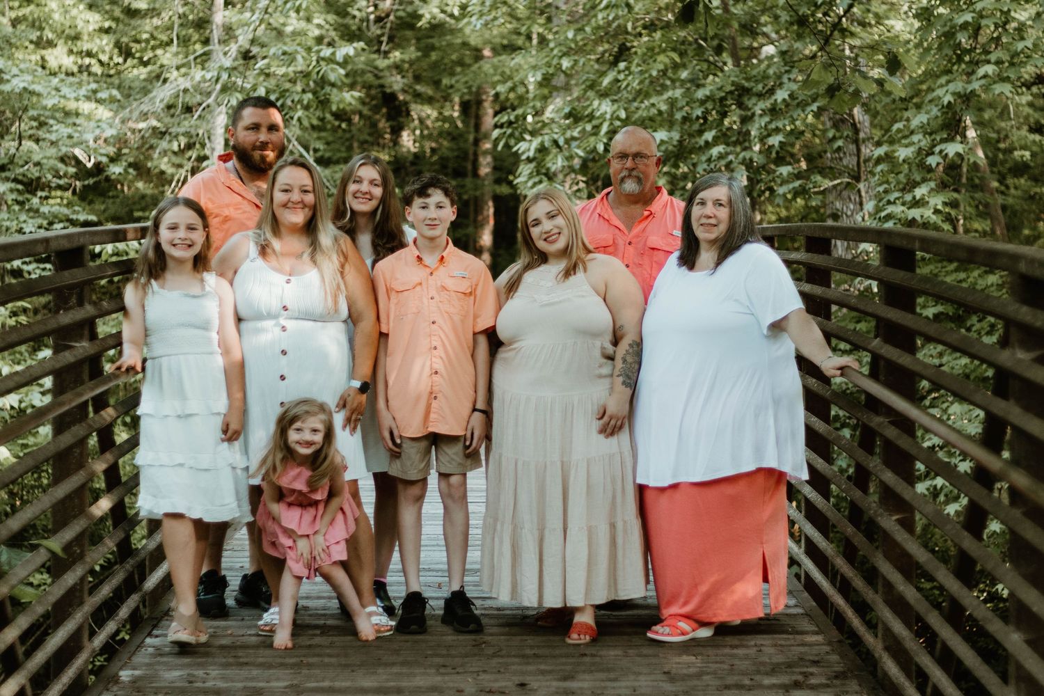 Group portrait of people wearing coordinated pastel outfits standing against a wooden fence at Victoria Bryant State Park in Georgia.