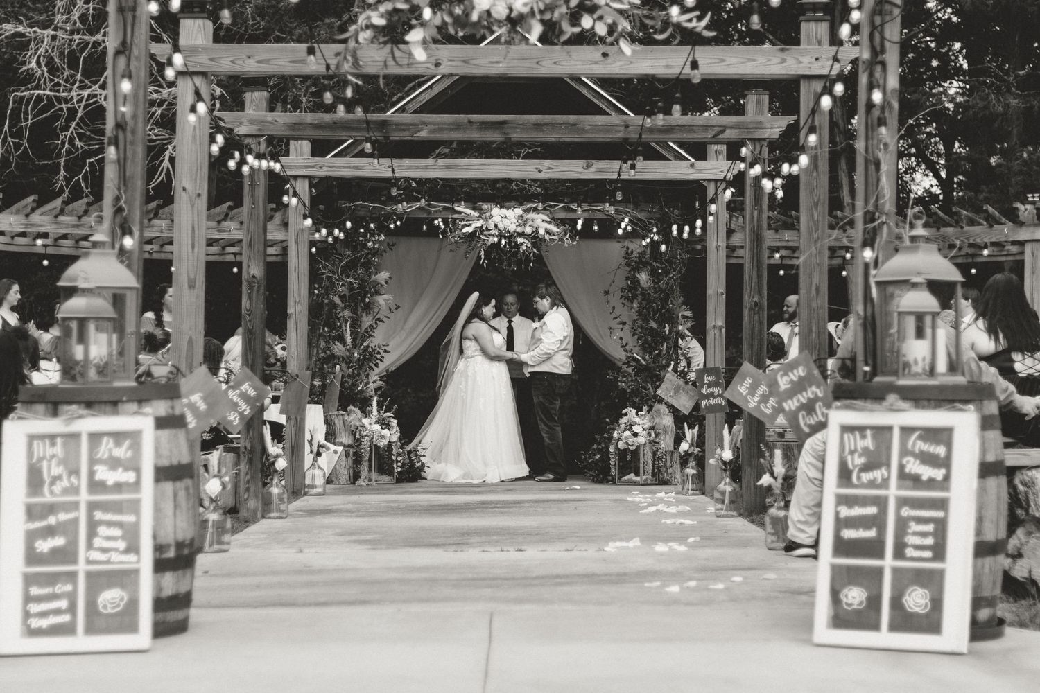 Black and white photo of wedding ceremony setup with decorated pergola and aisle markers at a wedding near Gainesville, Georgia.