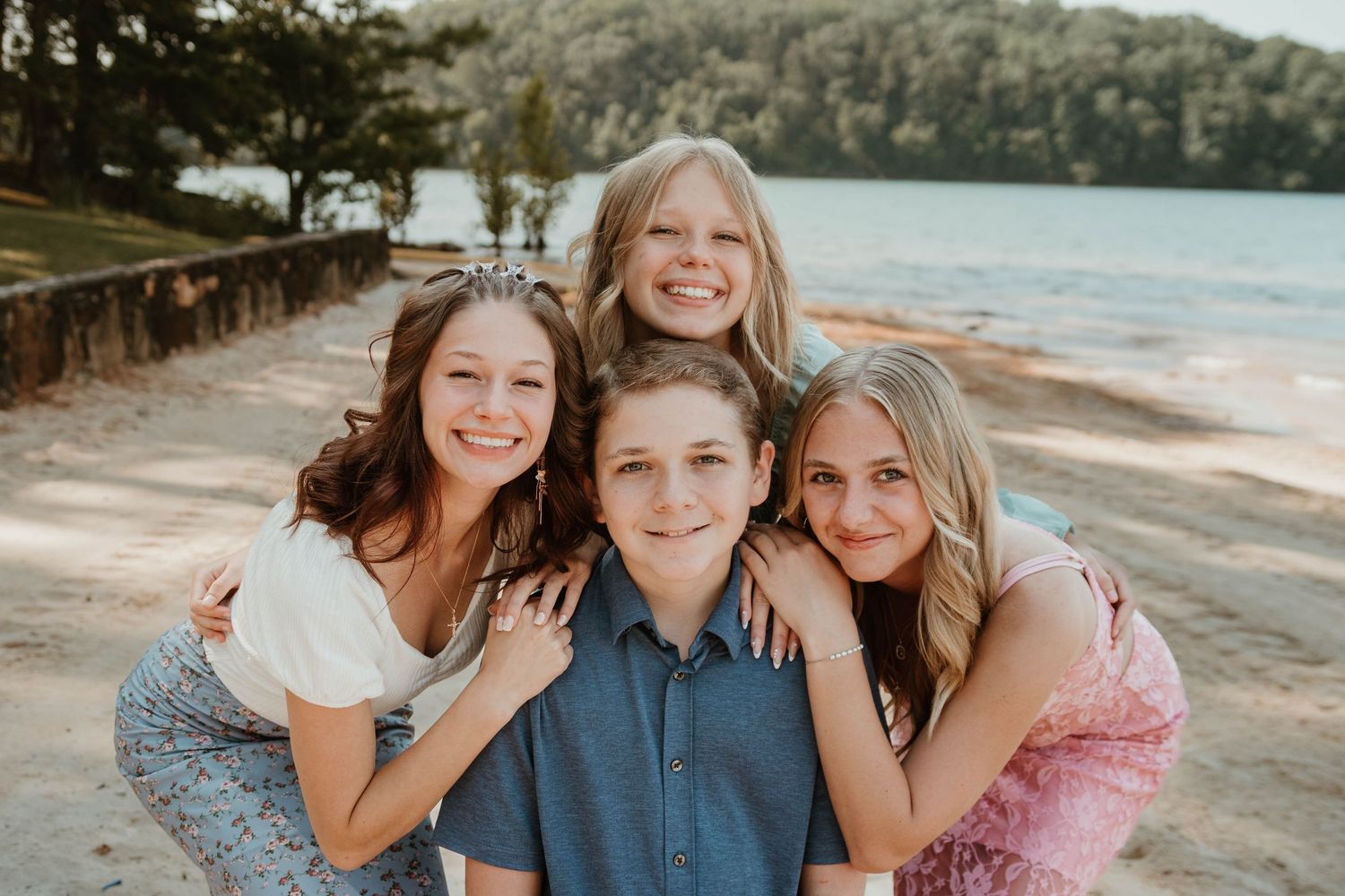 Four young cousins posing closely together on a sunny beach at Tugaloo State Park near Lake Hartwell.