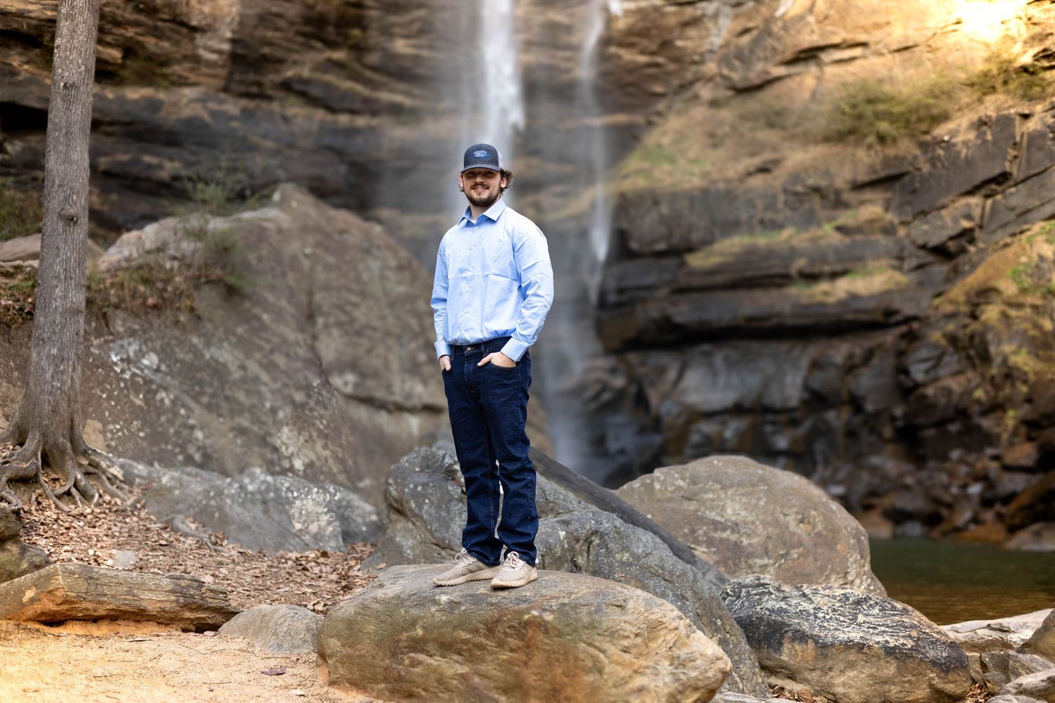 Light blue shirt and dark jeans ensemble photographed against scenic waterfall backdrop at Toccoa Falls College.