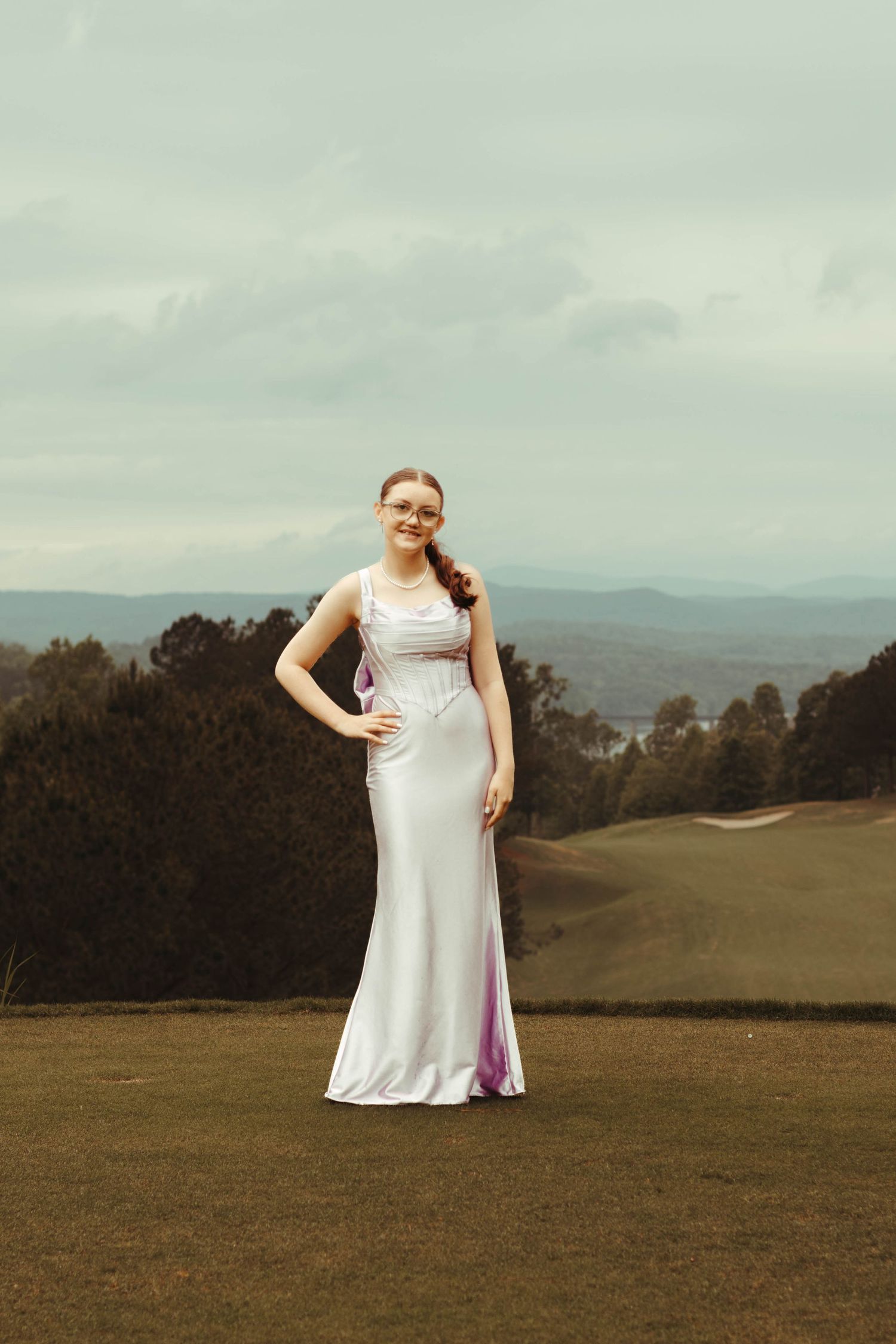 A person wearing a flowing lavender dress poses gracefully in a countryside setting at Currahee Club in northeast Georgia.