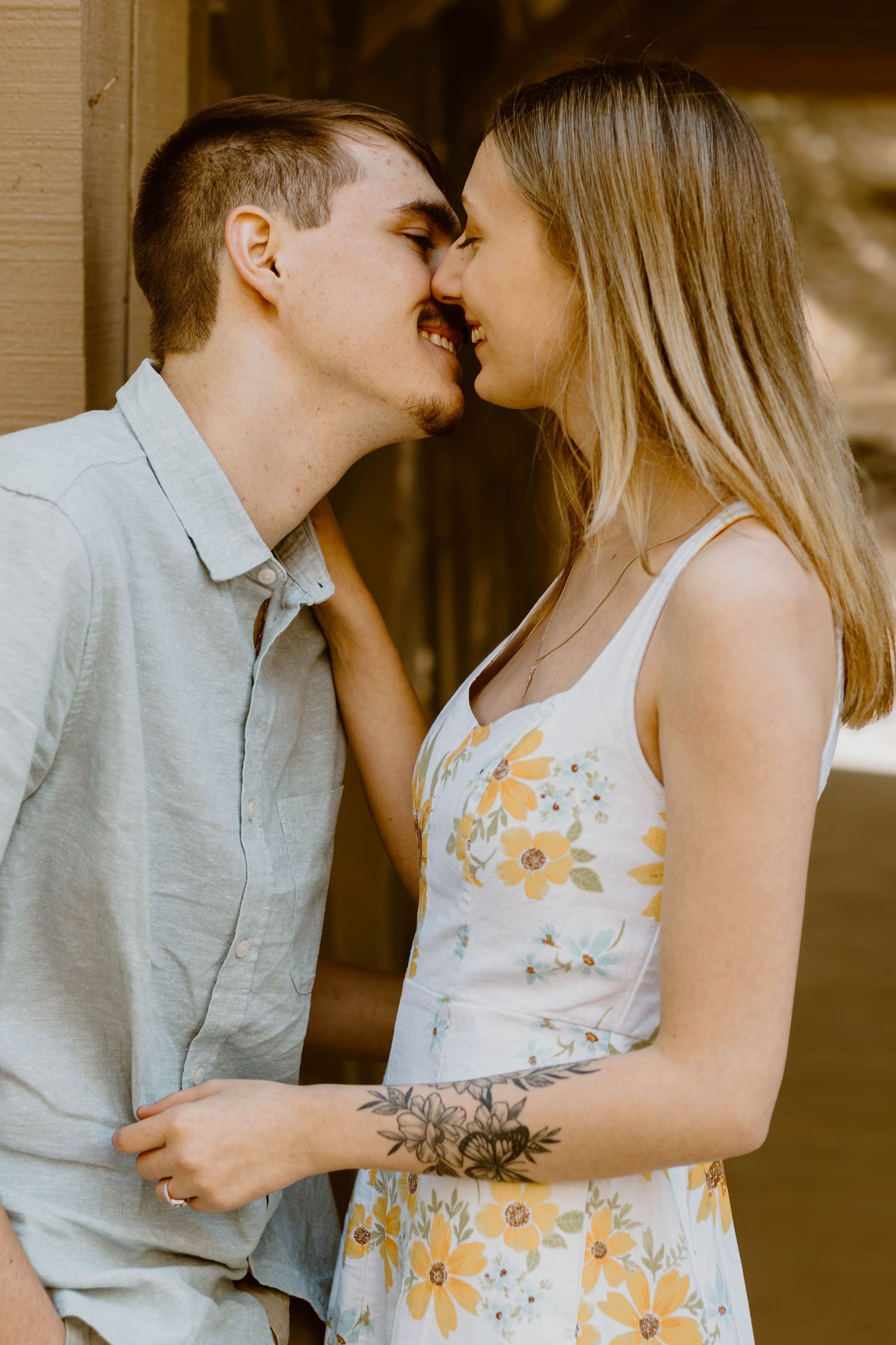 A romantic couple sharing an intimate moment together, with the woman wearing a floral sundress and the man in a gray shirt at a Toccoa park