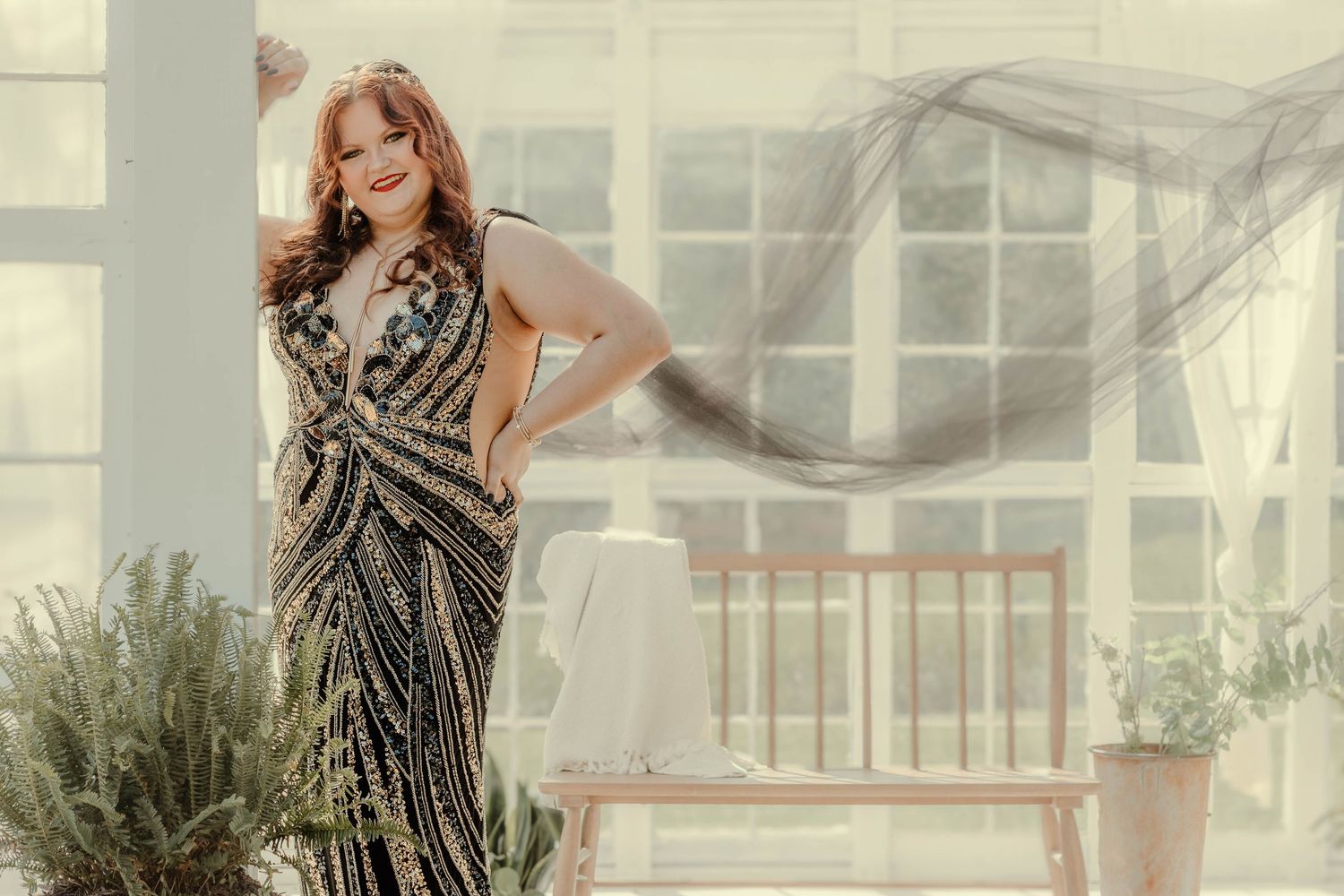 A glamorous sequined evening gown sparkles in a sunlit greenhouse setting with flowing fabric and potted plants at The Farm at Daffodil Hill