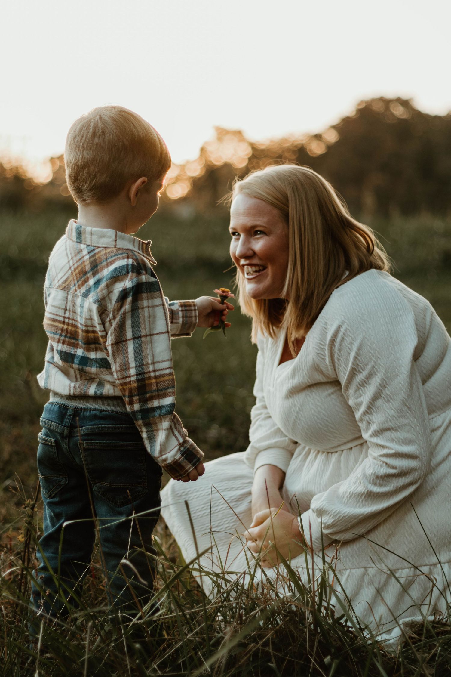 Parent and child share playful moments while sitting in grass during sunset at The Farm at Daffodil Hill in Clarkesville, GA.