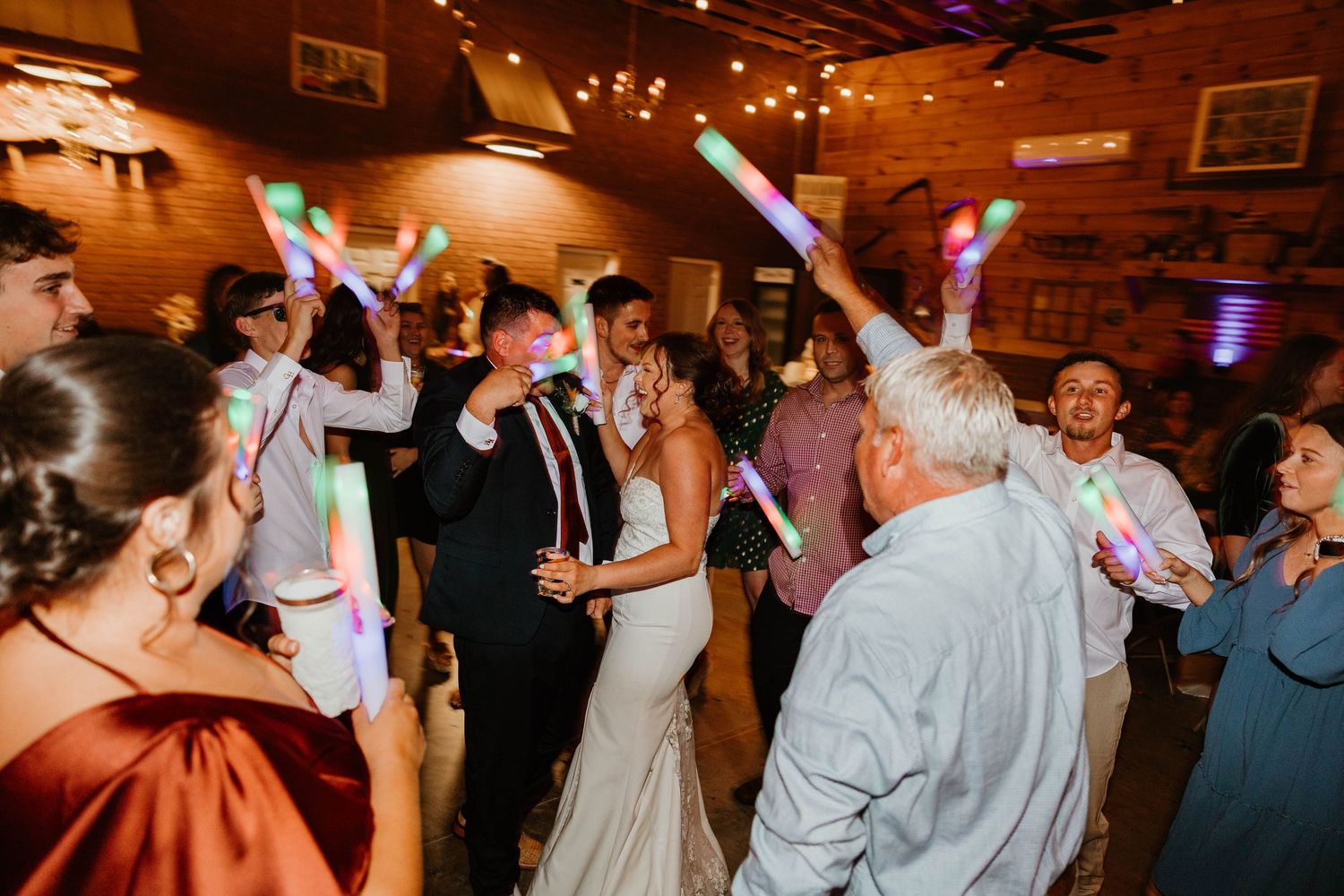 Wedding guests dance and celebrate together on a dimly lit dance floor during an evening reception.