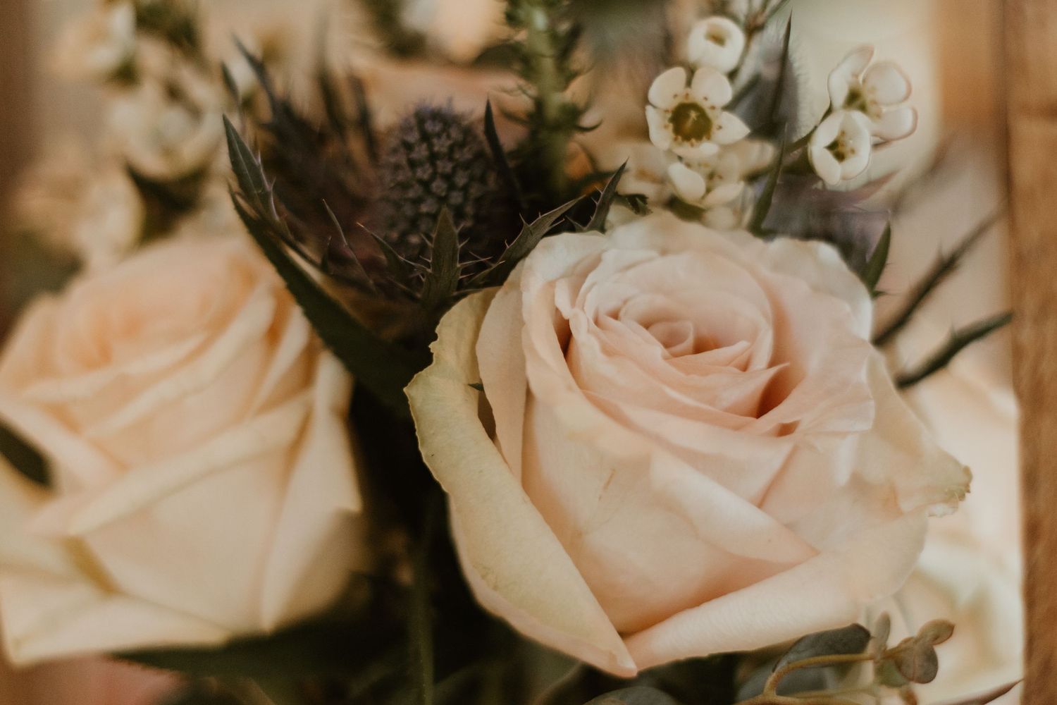 Elegant blush pink roses and white flowers in delicate wedding floral arrangement with green foliage.