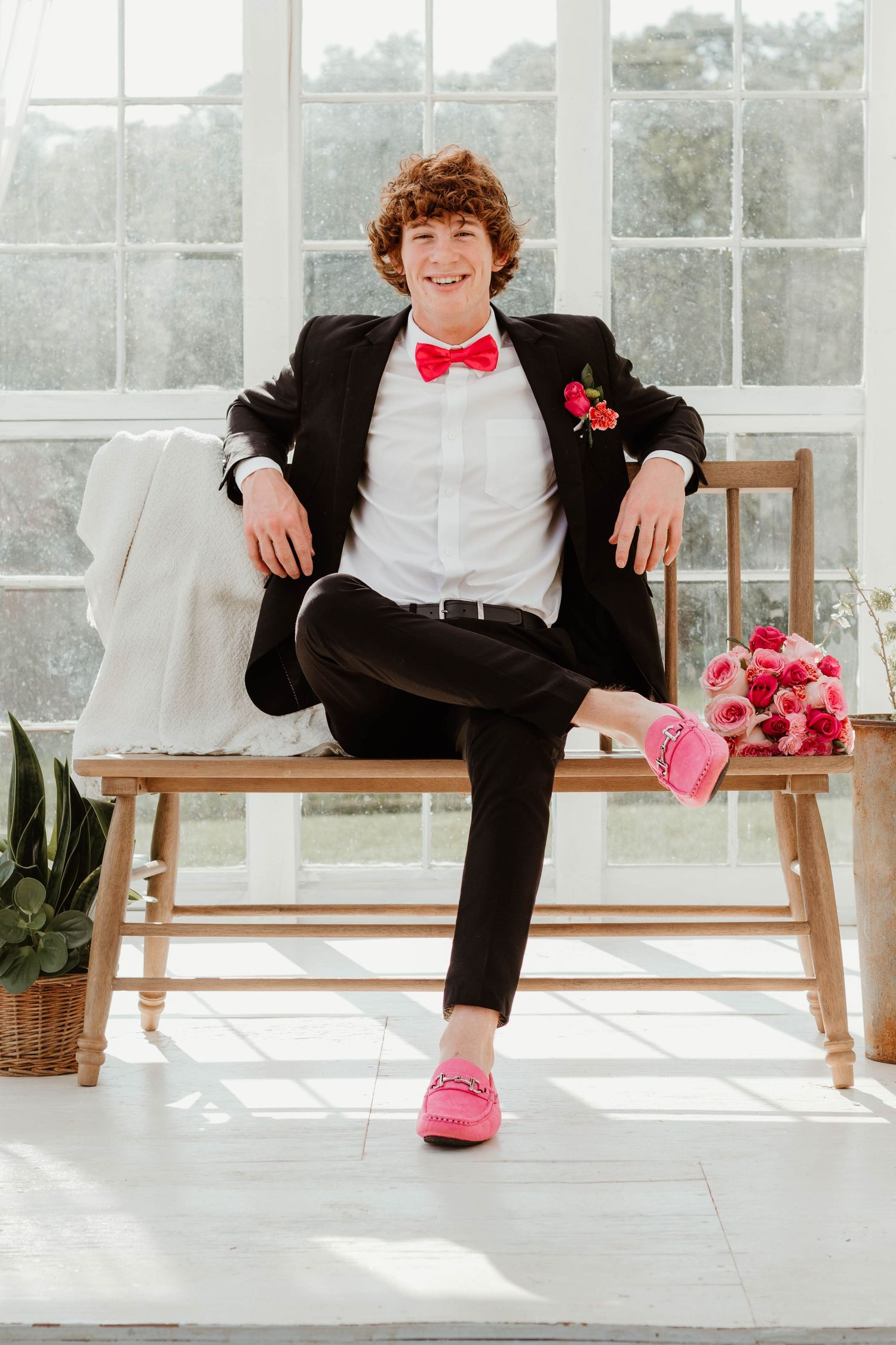 Stylish formal wear featuring pink accessories and a black suit in a bright greenhouse setting with flowers in northeast Georgia.