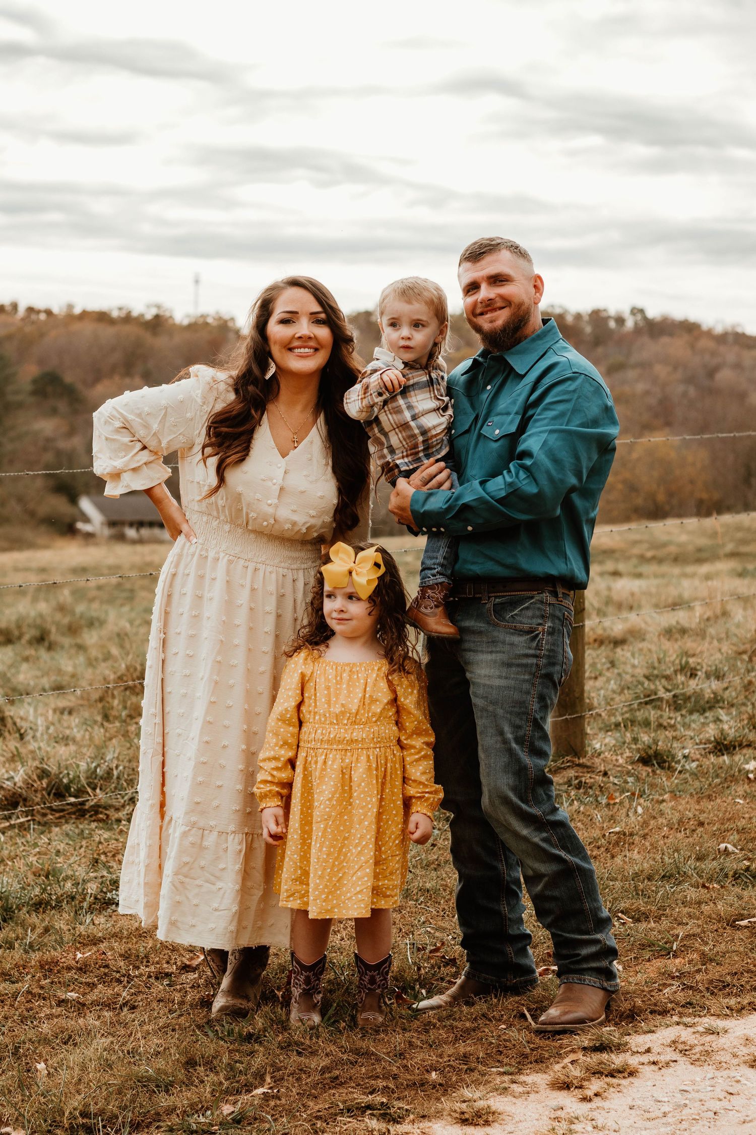 A family stands together in coordinating outfits against an autumn hillside backdrop in Clarkesville, Georgia.