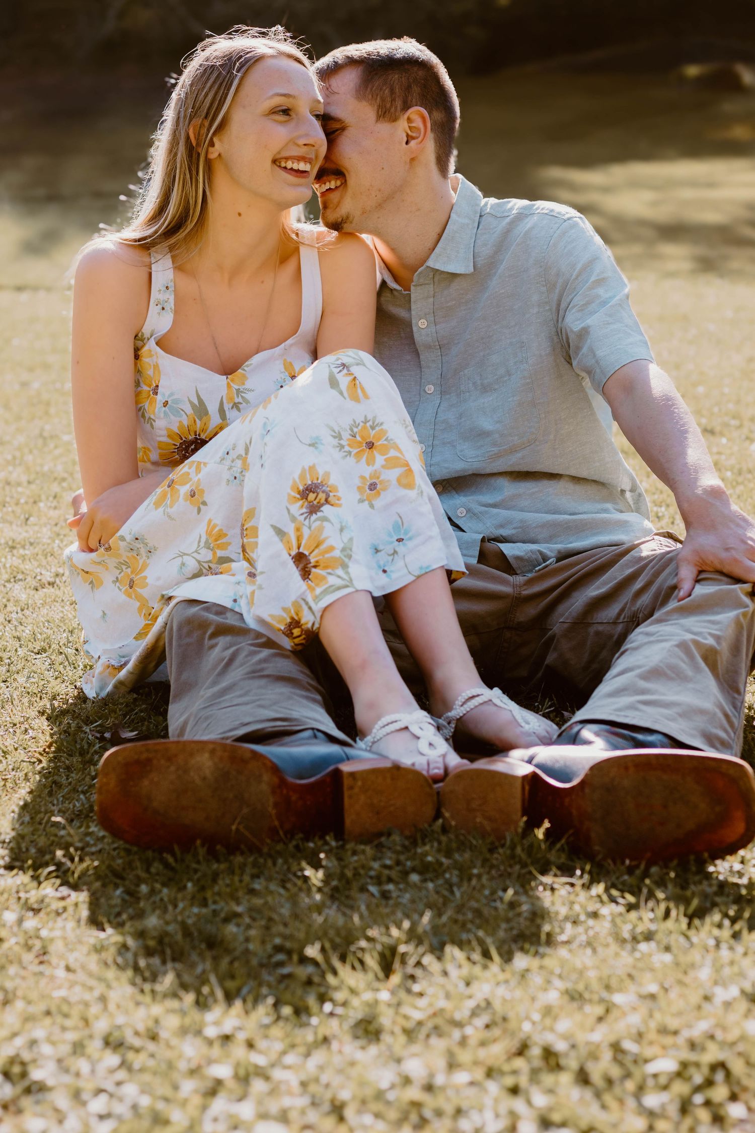 Couple laughing together while sitting on grass in warm sunlight at a park in northeast Georgia.