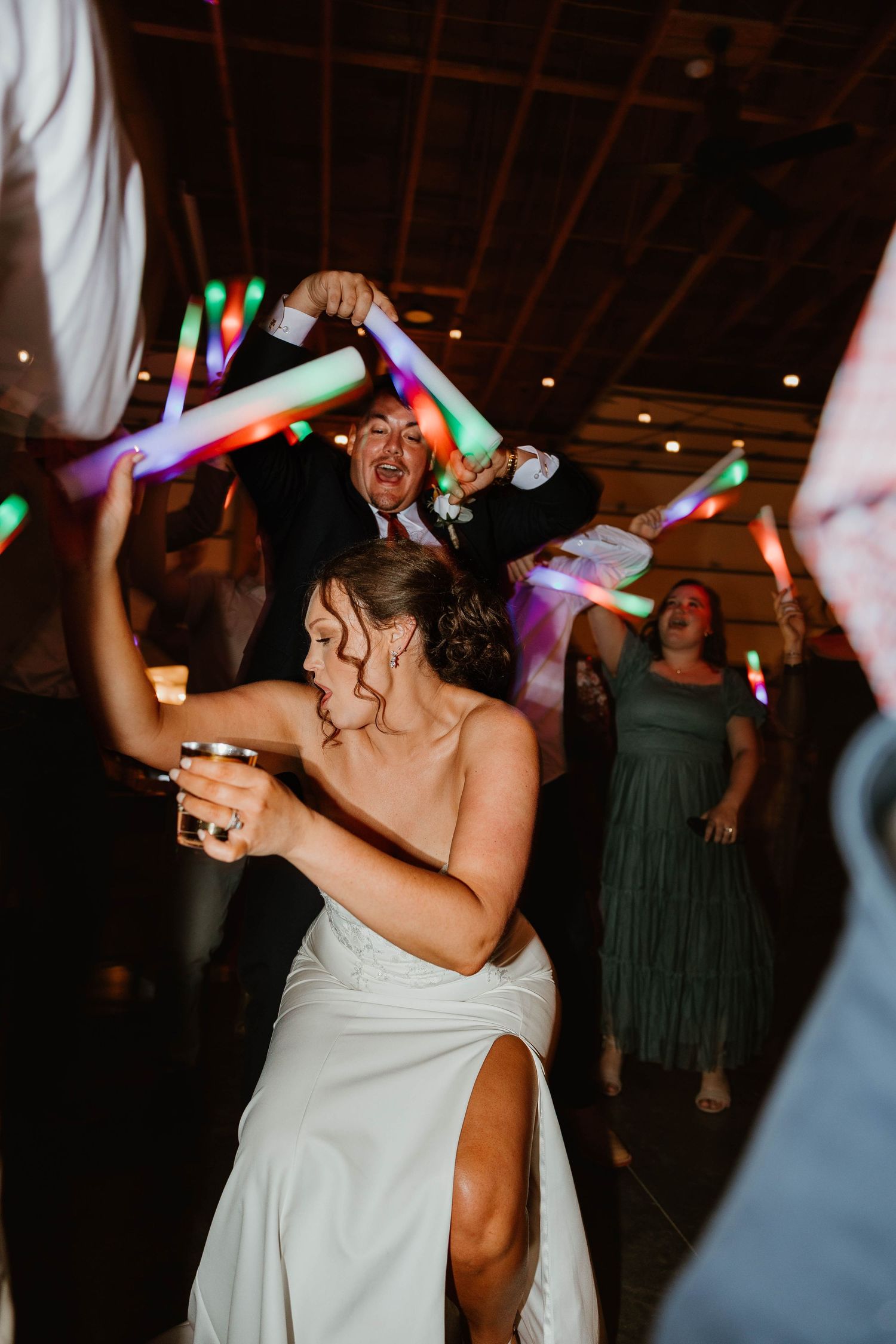 Wedding reception dance party with colorful light sticks and glowing effects creating a festive atmosphere.