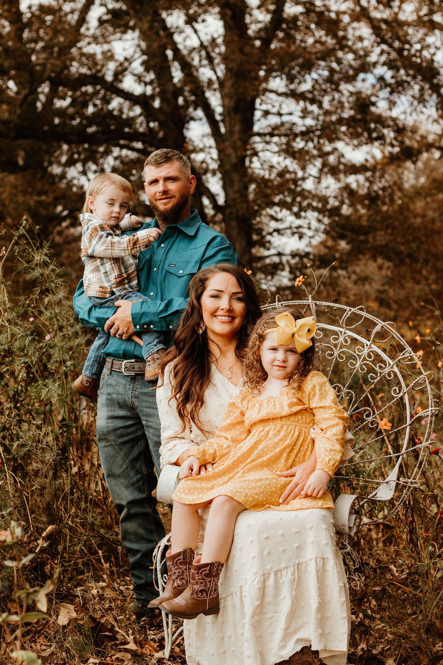 Family poses together outdoors with decorative garden elements in warm autumn lighting at The Farm at Daffodil Hill in northeast Georgia.