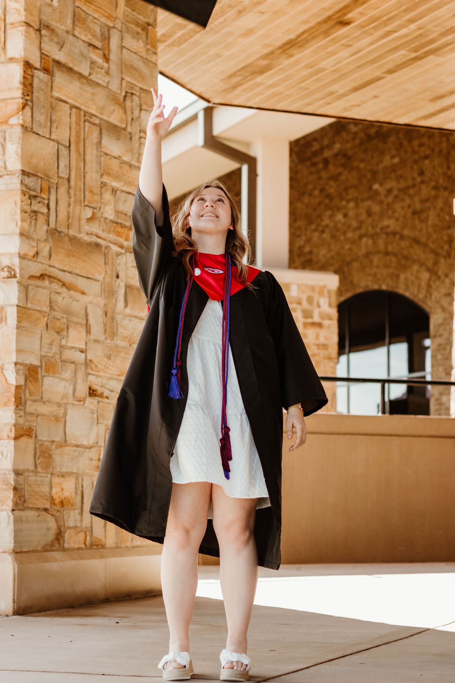 A graduate in cap and gown reaching upward during a celebratory photoshoot in northeast Georgia.