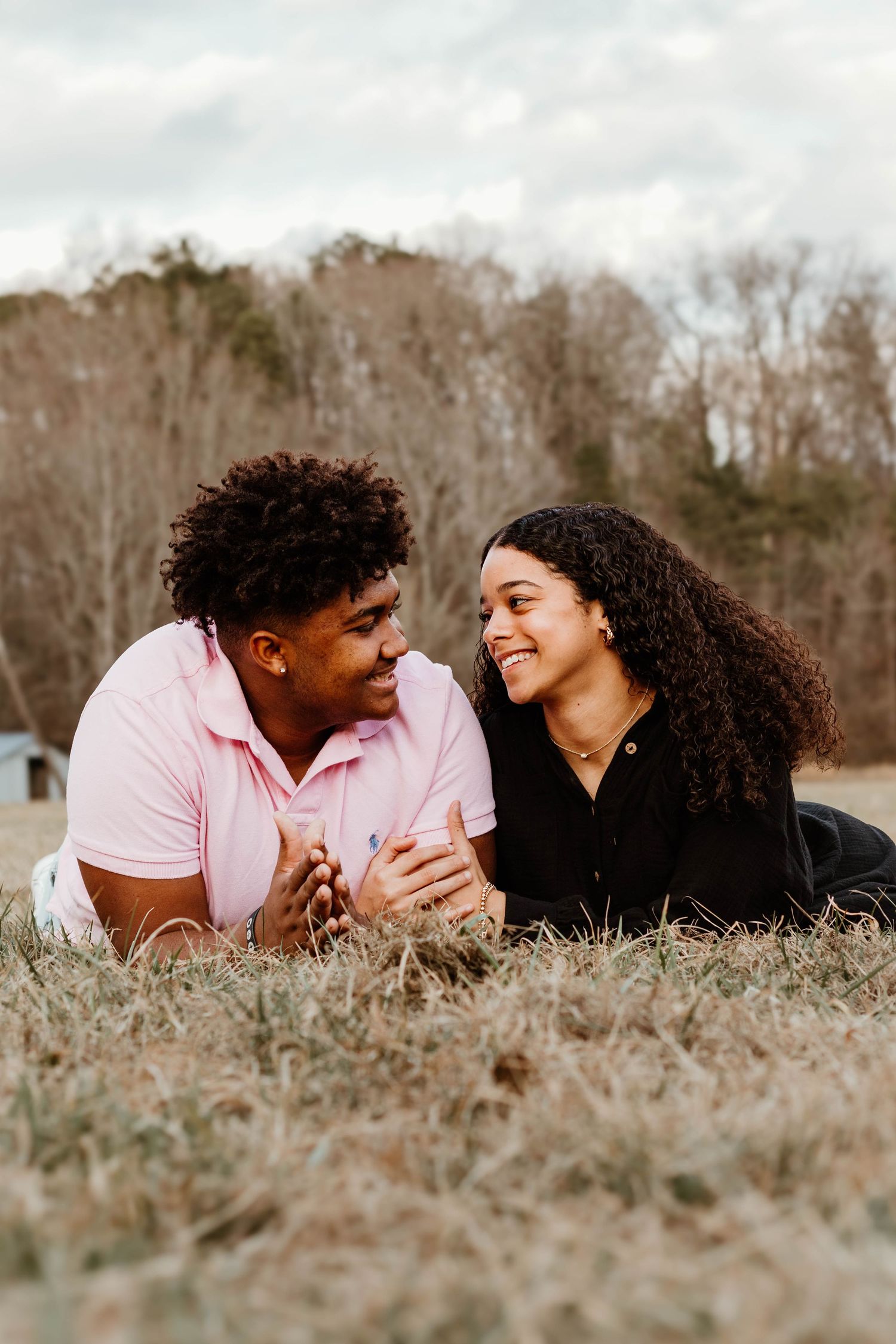 A couple lies in the grass together sharing a joyful moment in a field on an overcast day at Geary Farm in Toccoa, GA.