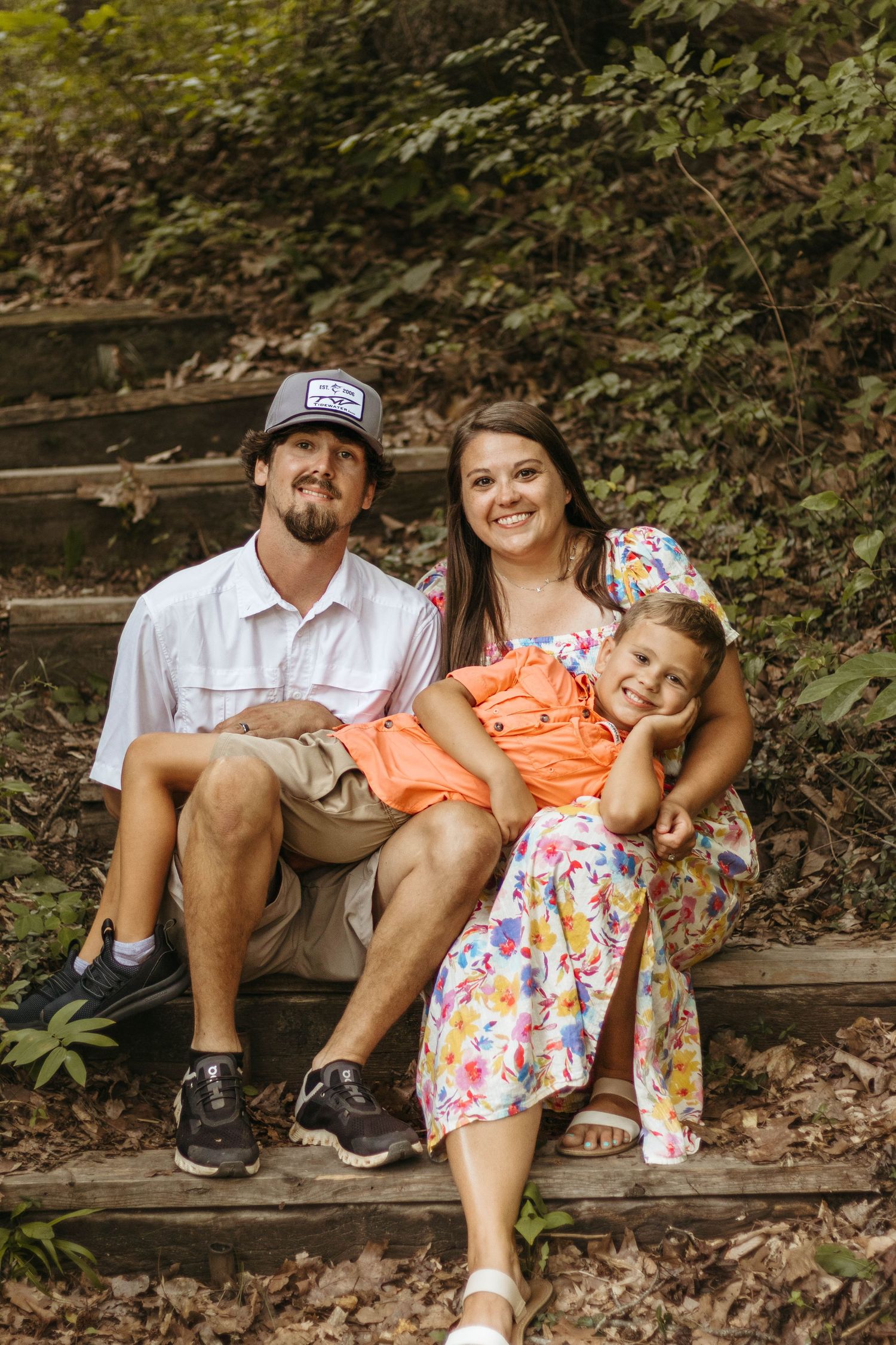 Family portrait on rustic wooden steps surrounded by lush greenery at Henderson Falls Park.