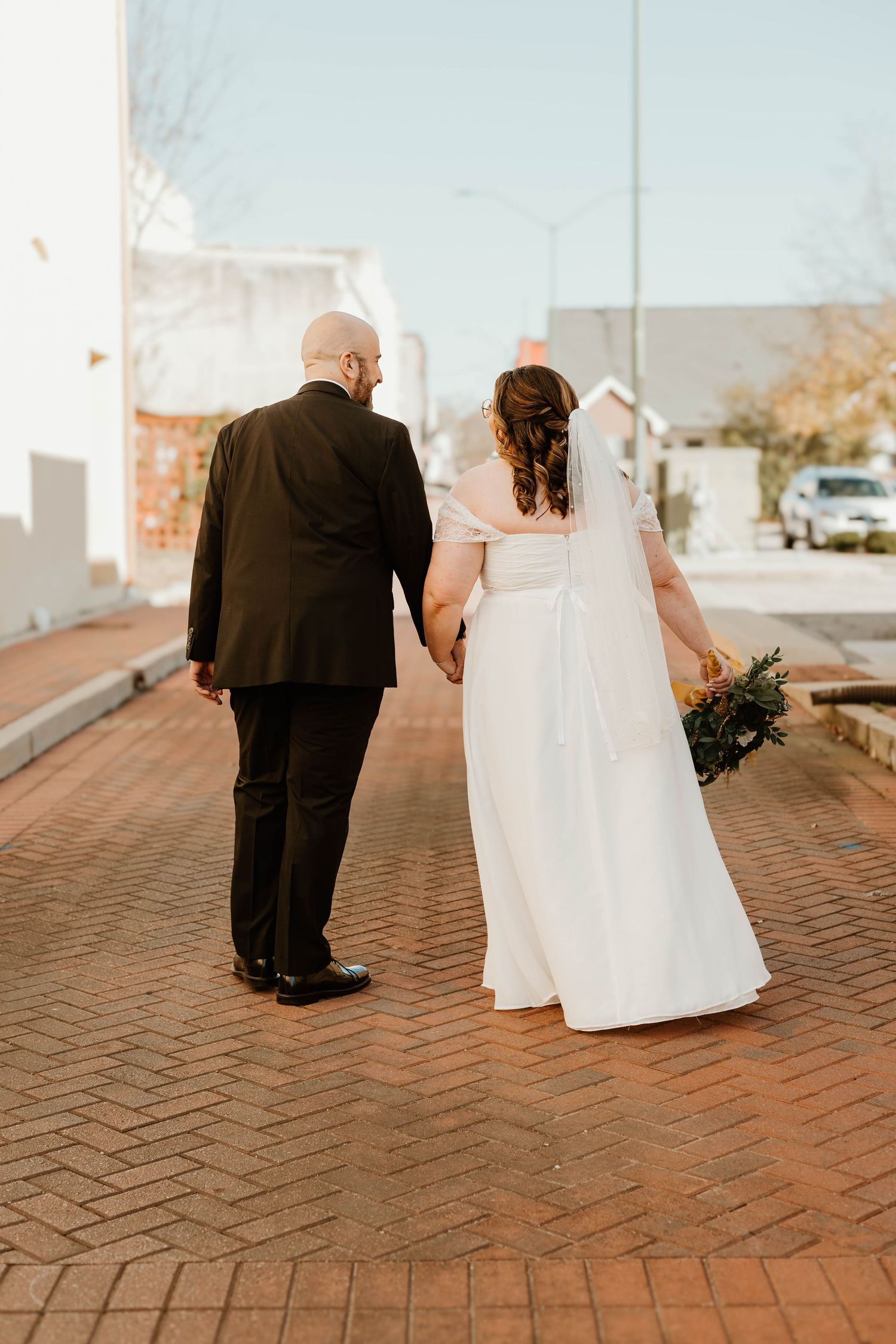 Couple in wedding attire walking together on red brick pathway showing three progressive shots of their movement.