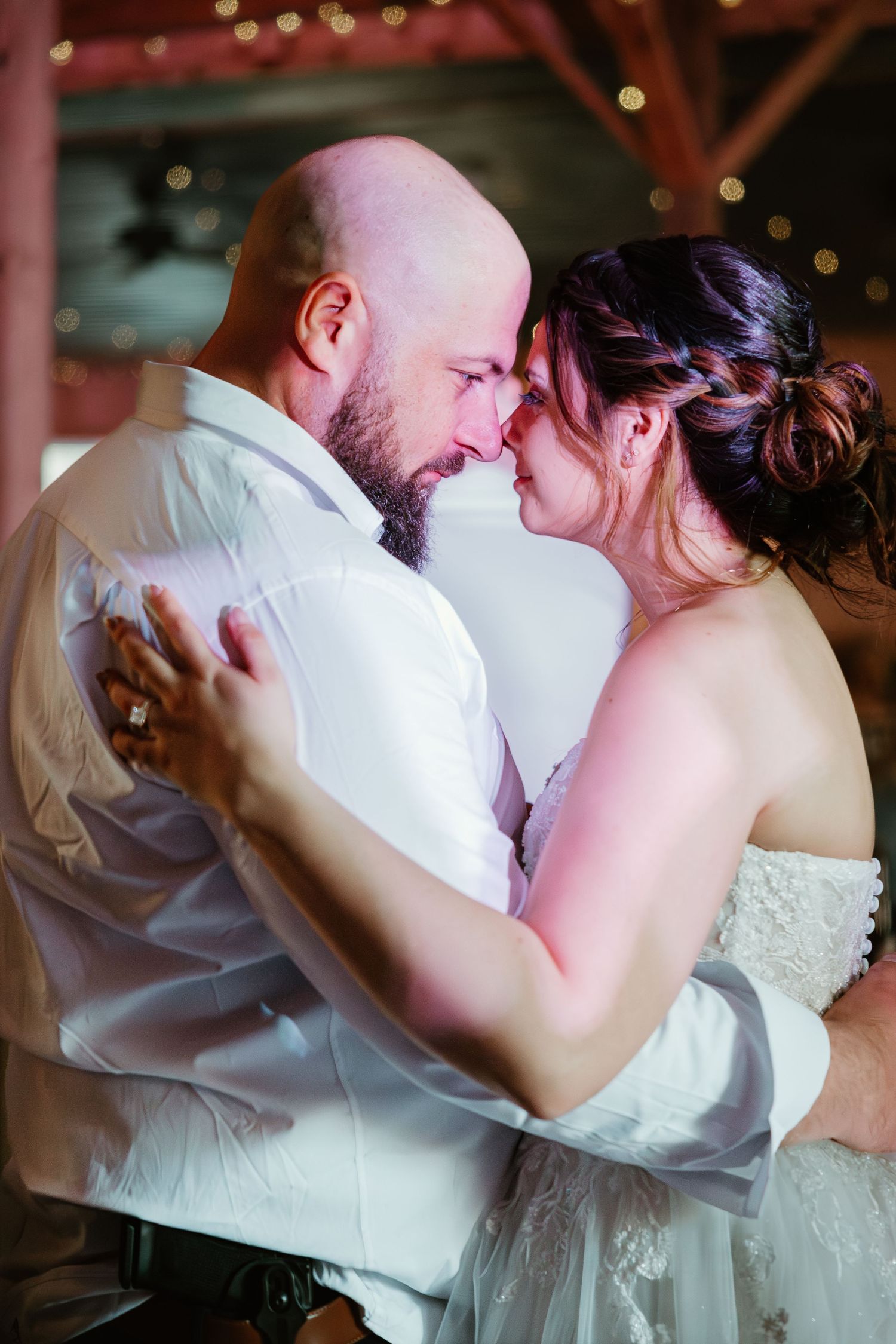 Bride and groom sharing an intimate forehead touch during their first dance at a romantic barn wedding reception.