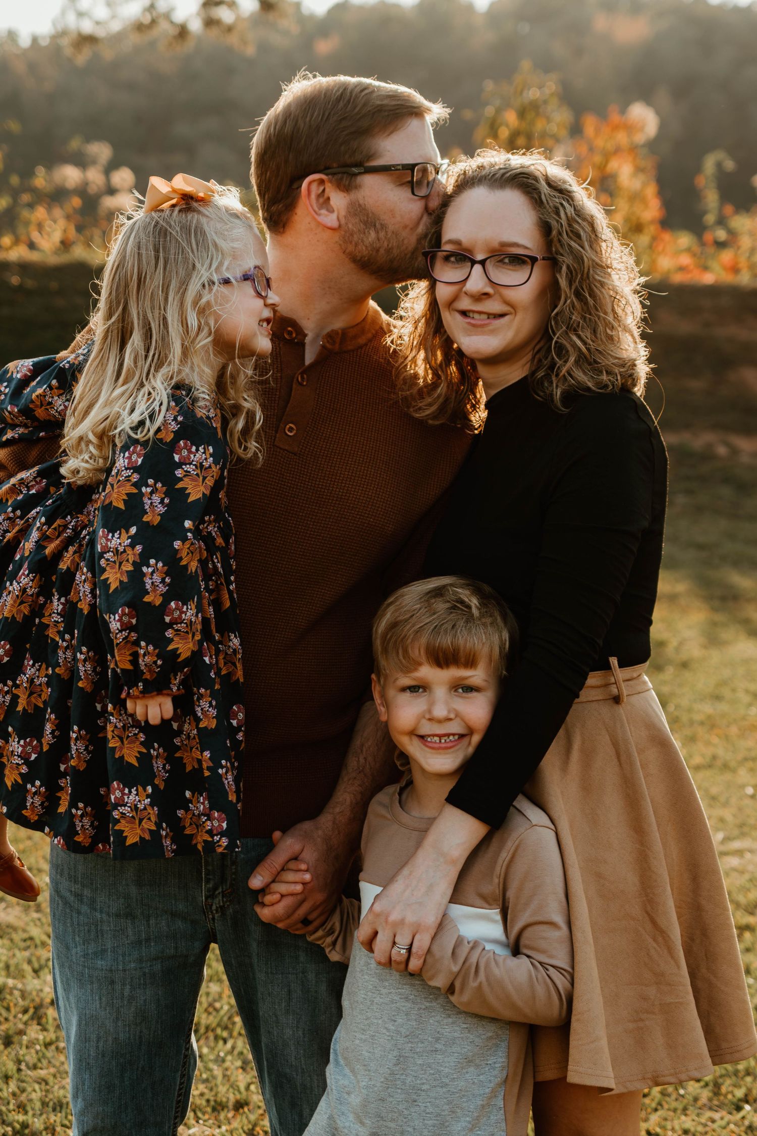A family shares tender moments together during a golden hour photoshoot in an autumn field.