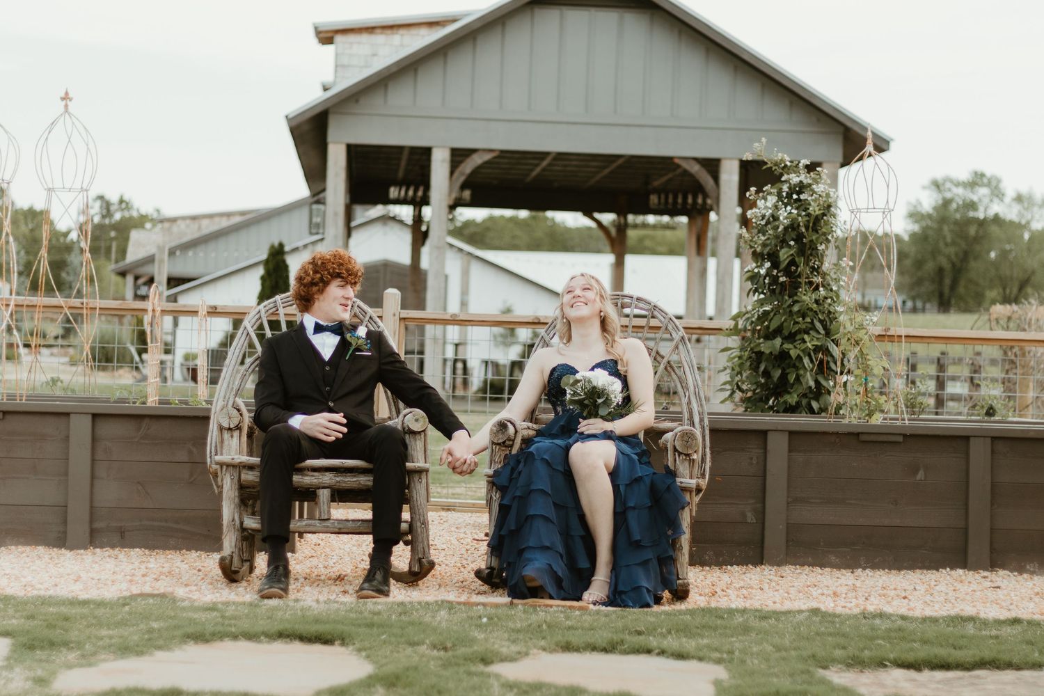 A couple sits on a rustic bench enjoying a playful moment together at The Venue at Broken Bridges in Northeast Georgia.