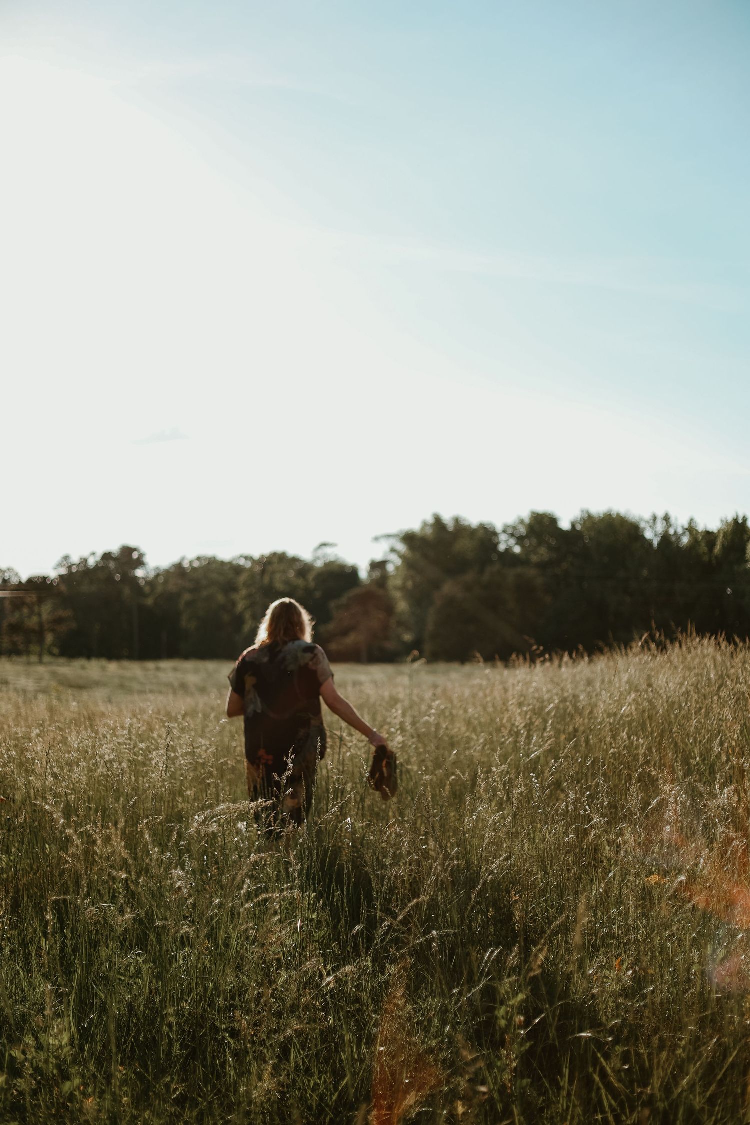 A silhouetted person walking through a tall grass meadow at sunset in northeast Georgia.