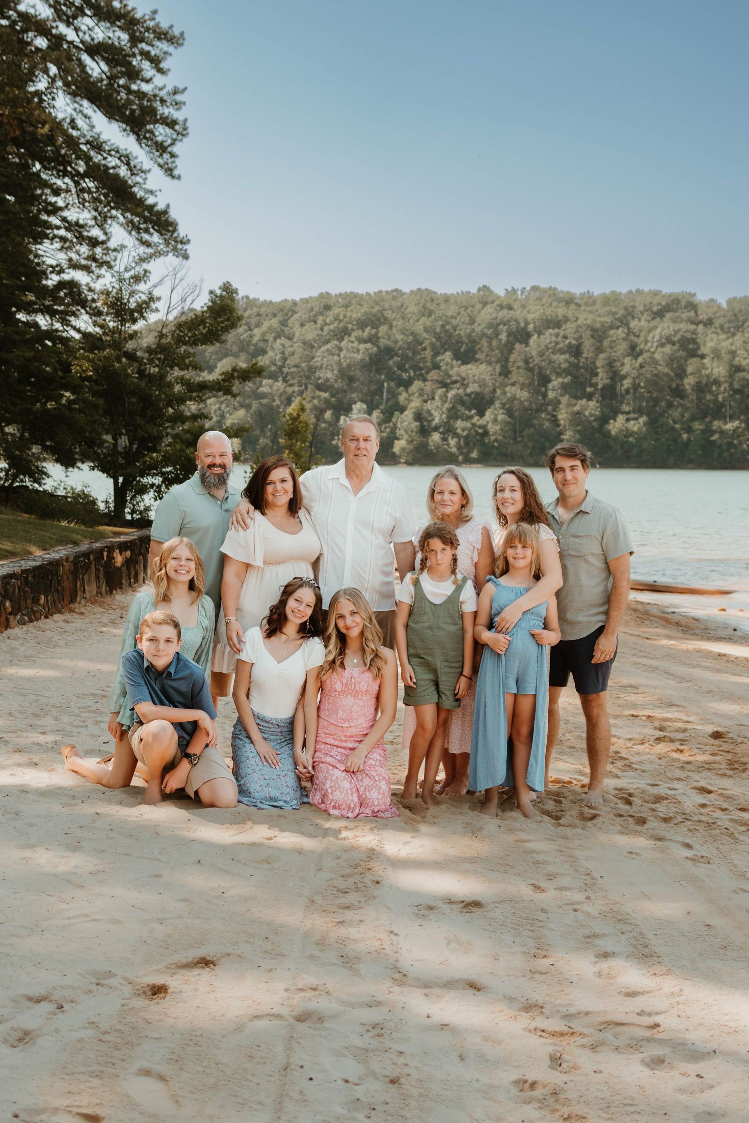 Large family group portrait at a scenic lakeside beach with pine trees and hills in background at Tugaloo State Park in northeast Georgia.