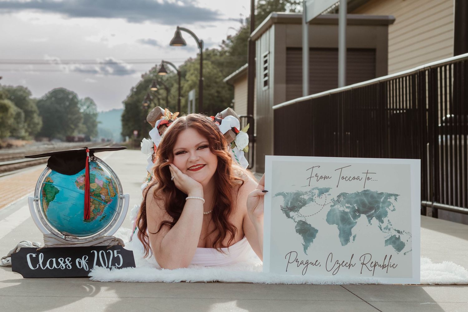 A graduation photo setup with a globe and world map display on a train platform in Toccoa, GA.