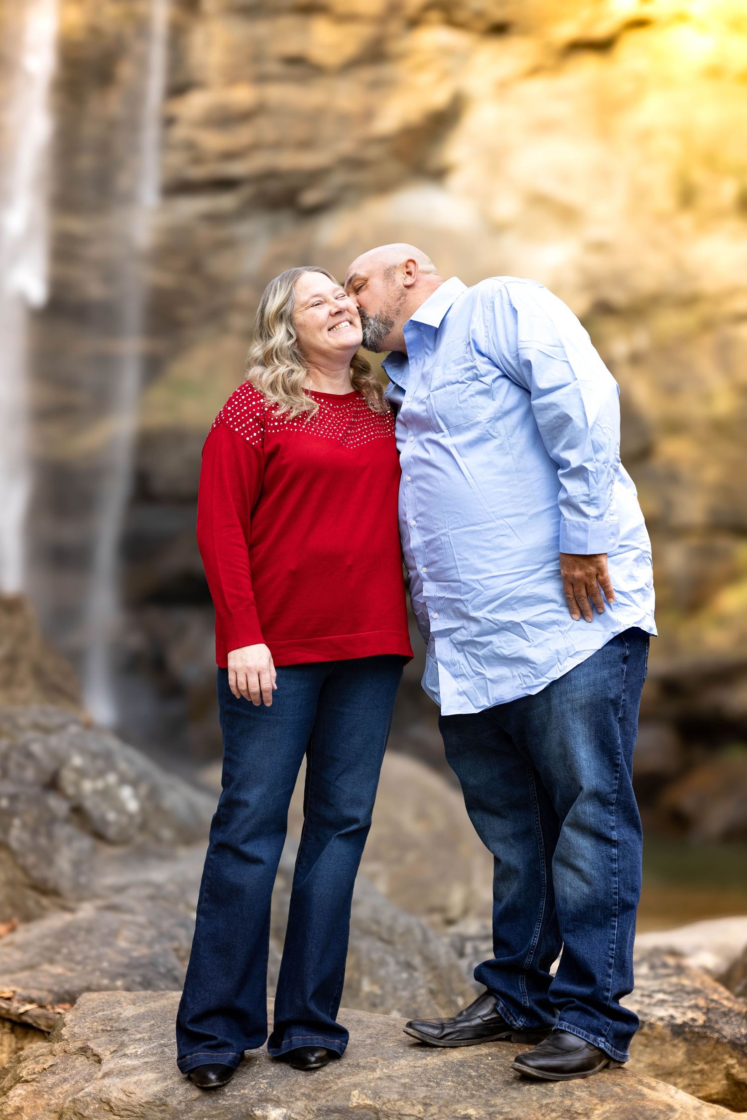 Couple sharing a tender moment by Toccoa Falls with golden sunlight in background.