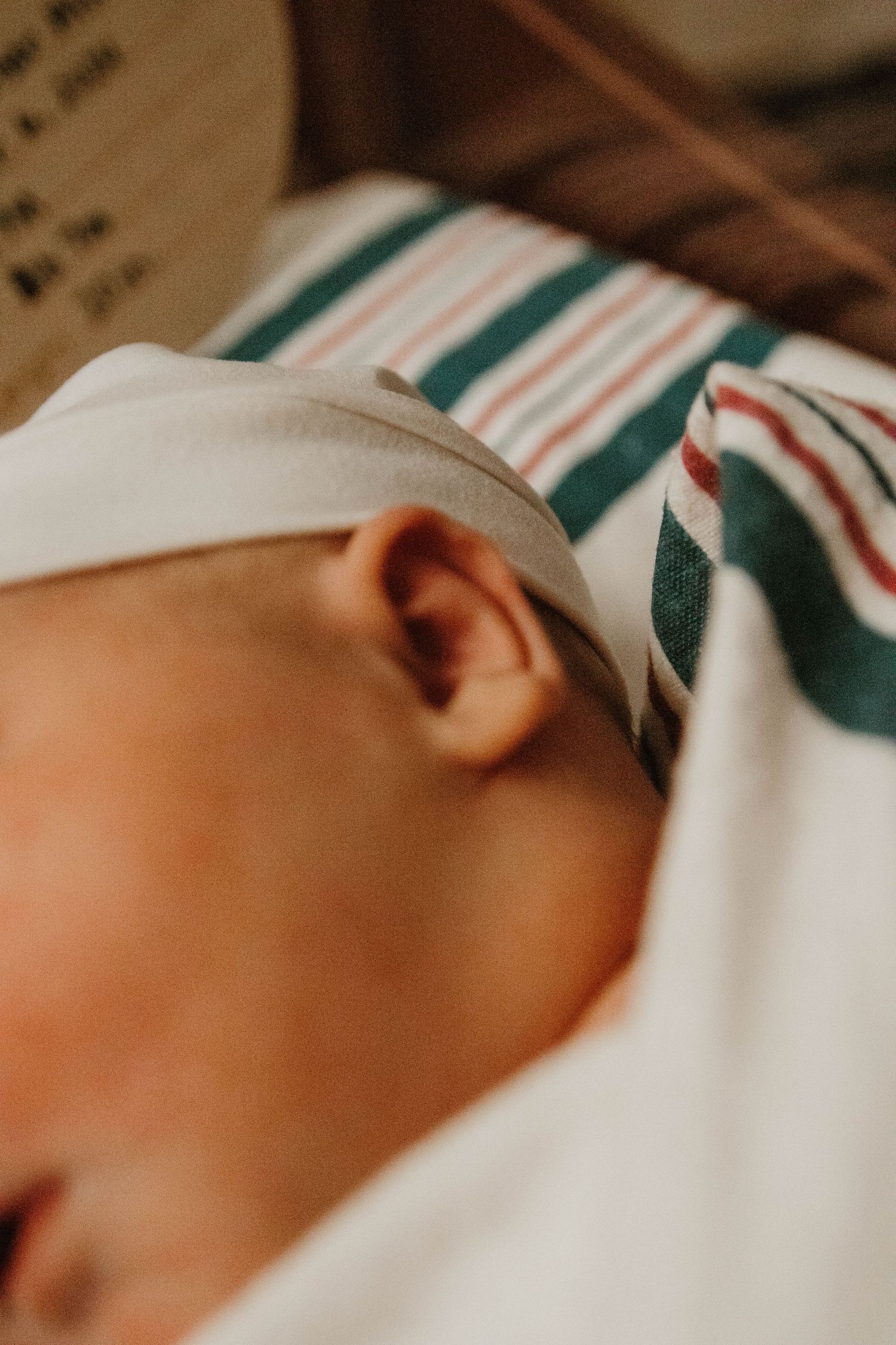 Peaceful close-up of sleeping infant swaddled in white with green and red striped hospital bassinet in northeast Georgia.