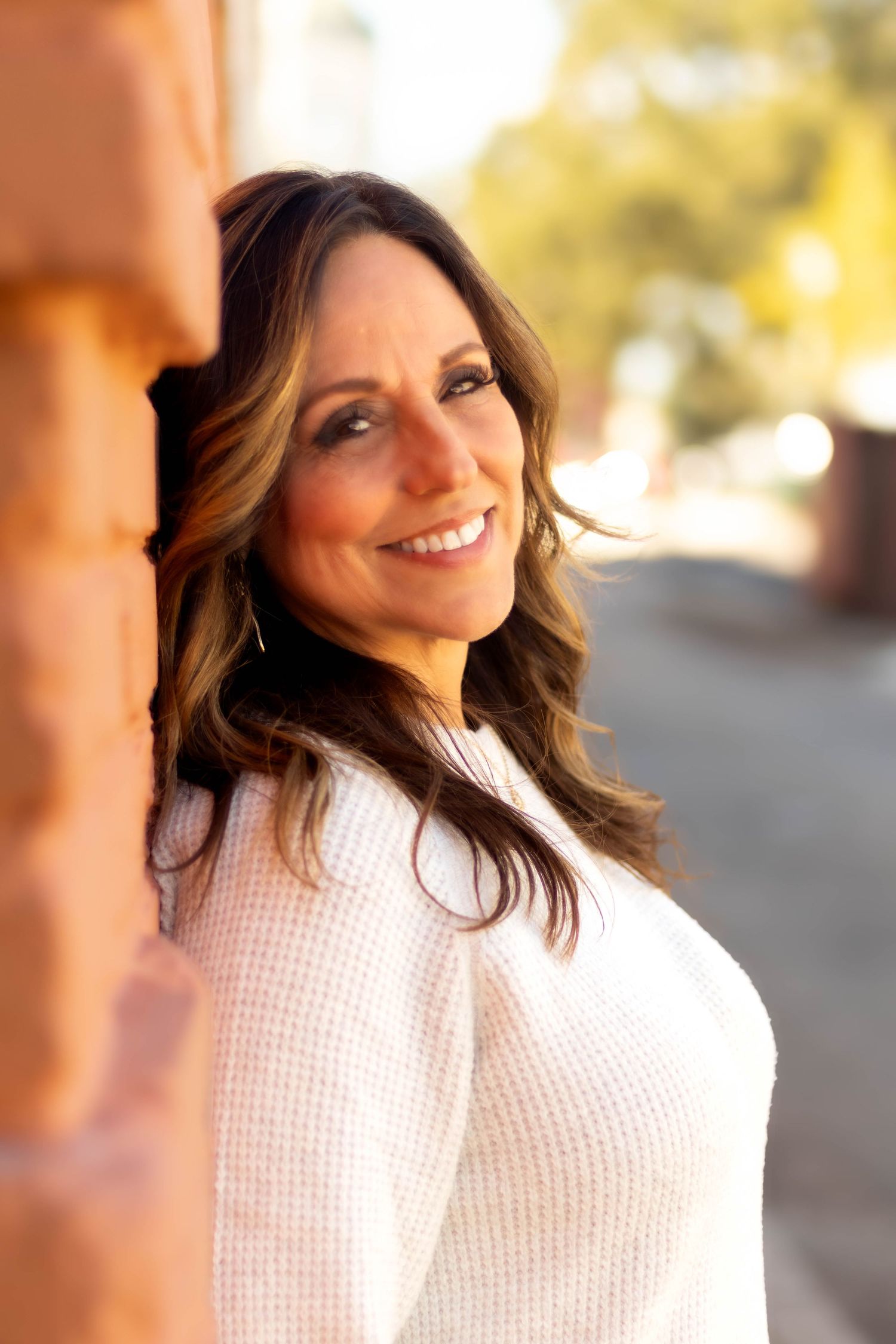 Portrait of a person in a white sweater smiling warmly in natural lighting in downtown Toccoa.