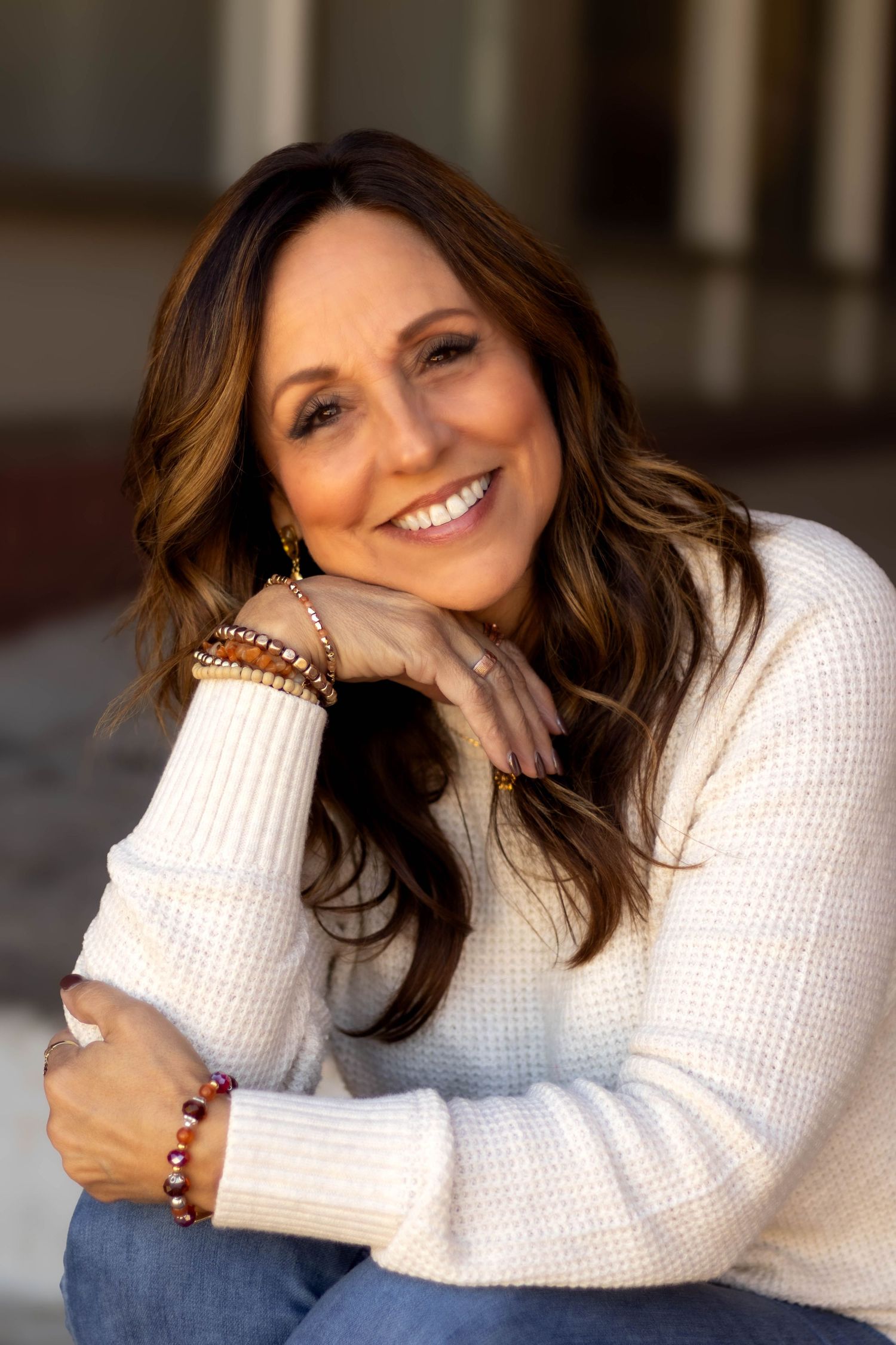 Portrait of a person in cream sweater wearing beaded bracelets with a joyful expression in downtown Toccoa, GA.
