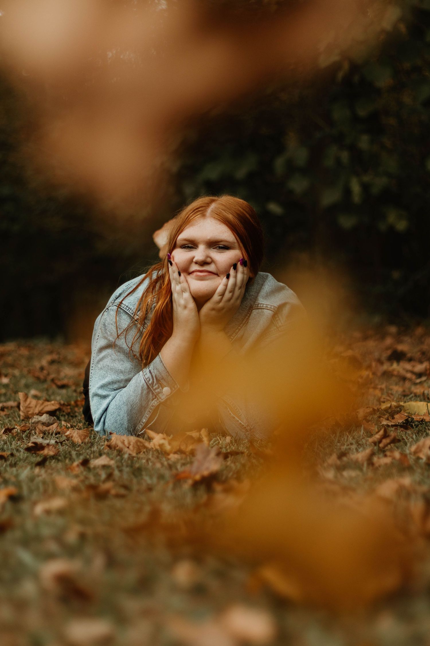 Person lying in fallen autumn leaves during an outdoor photography session at Henderson Falls Park in Toccoa.