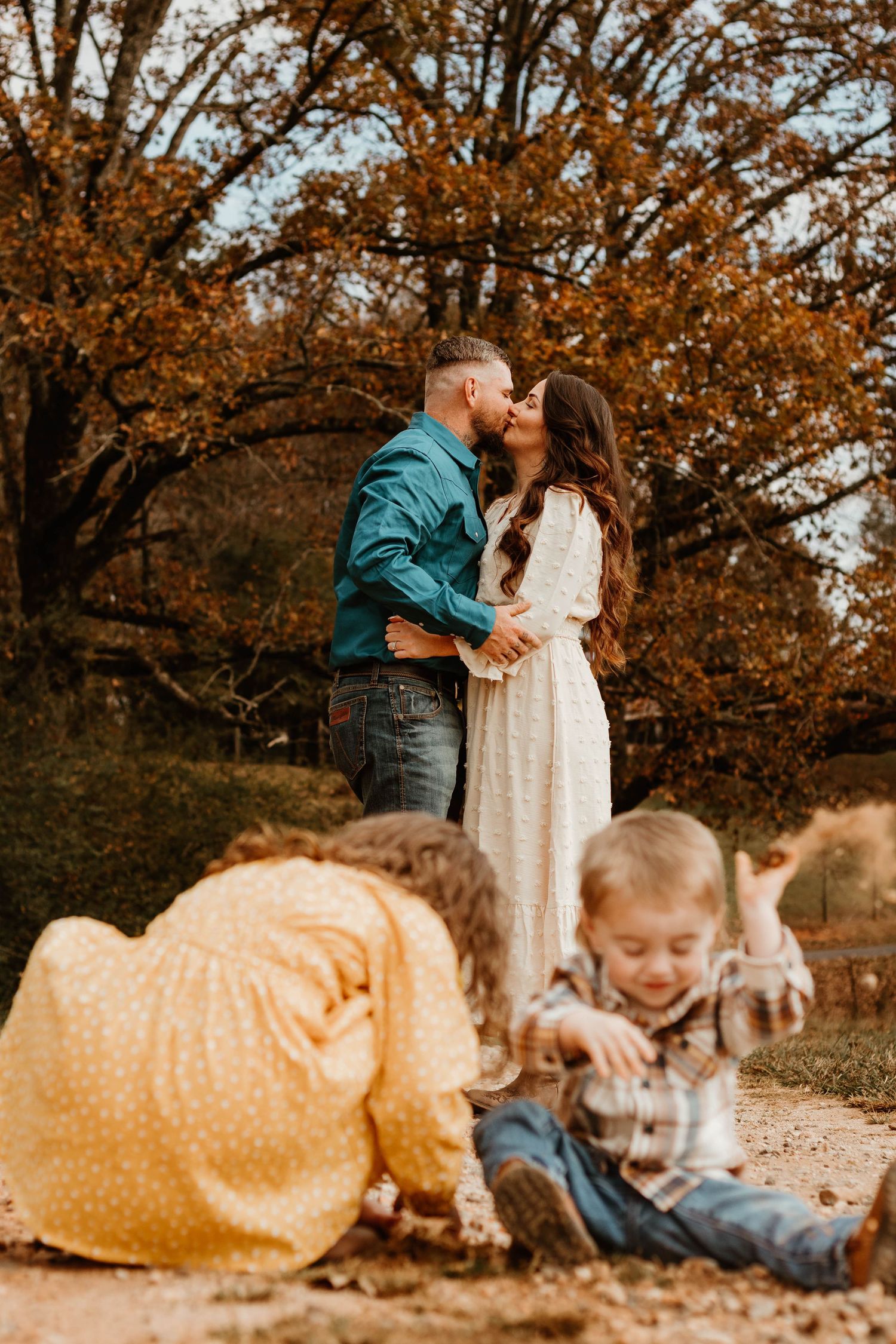 Fall family photos with couple in teal and white against autumn background with children playing in northeast Georgia.