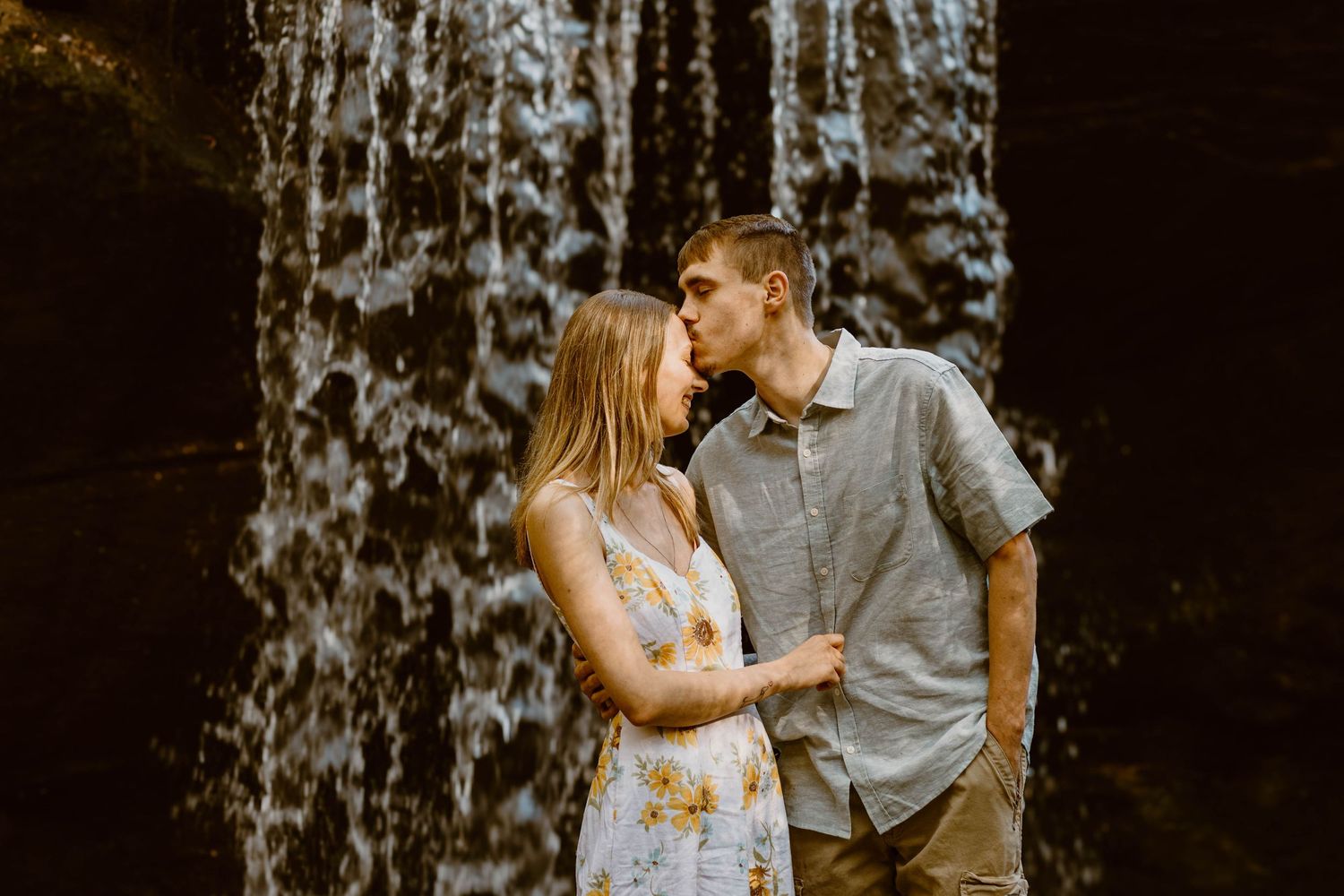 Couple embracing in front of waterfall during golden hour outdoor photoshoot at Henderson Falls in northeast Georgia.