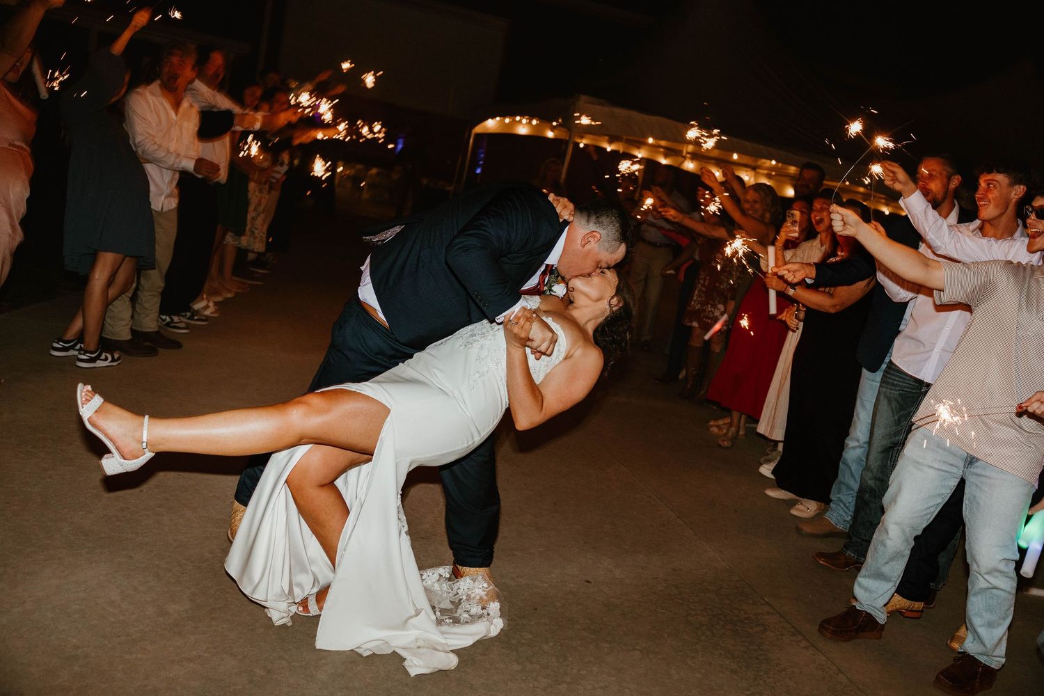 Wedding guests dance and celebrate during a lively reception party at night.