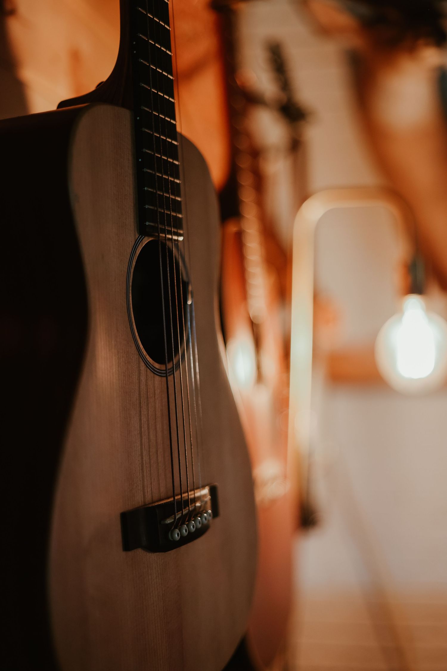 Close-up of an acoustic guitar body and strings in moody amber lighting in Toccoa, GA.
