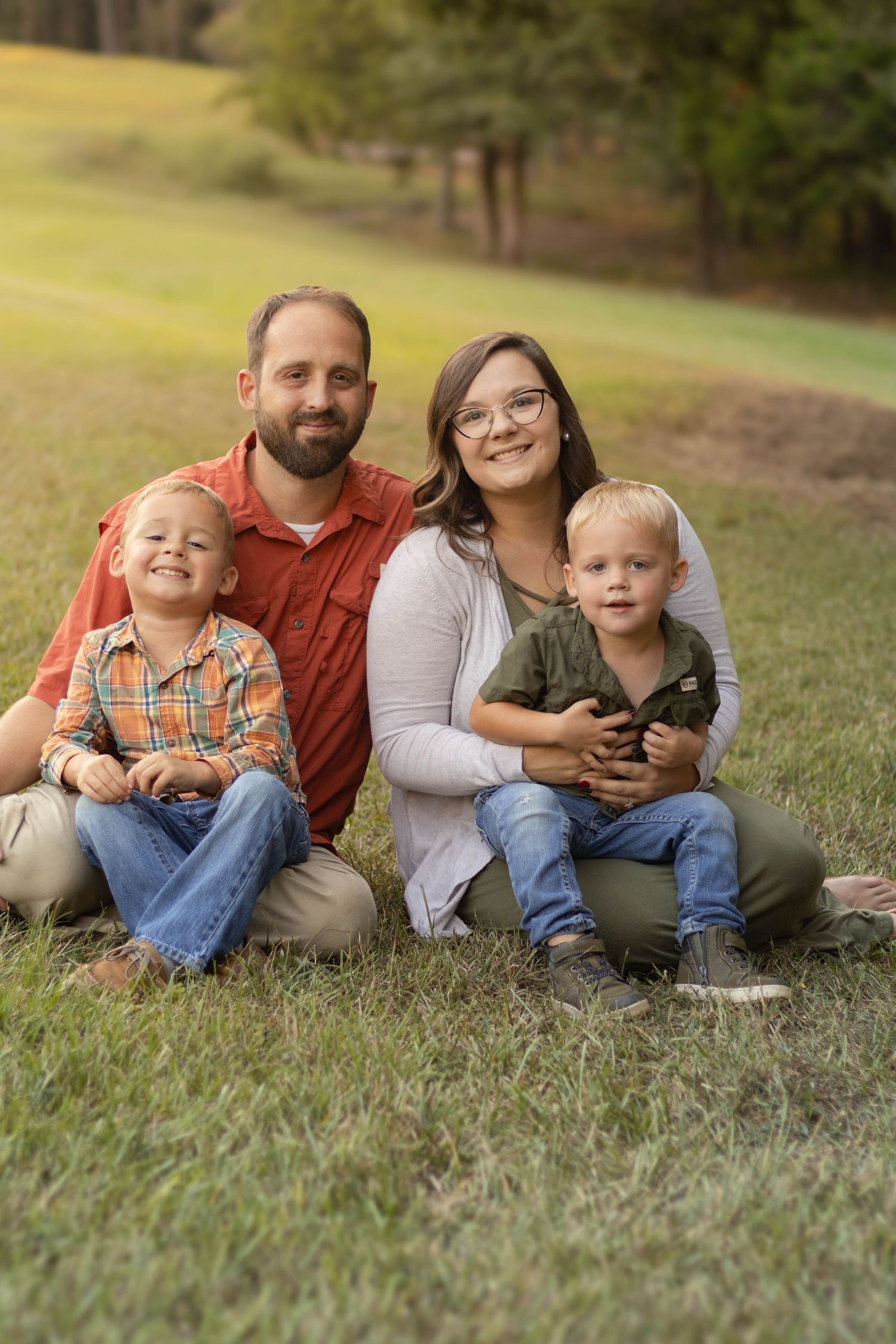 Family lying together on grass during an outdoor photo session at Geary Farm in Georgia.