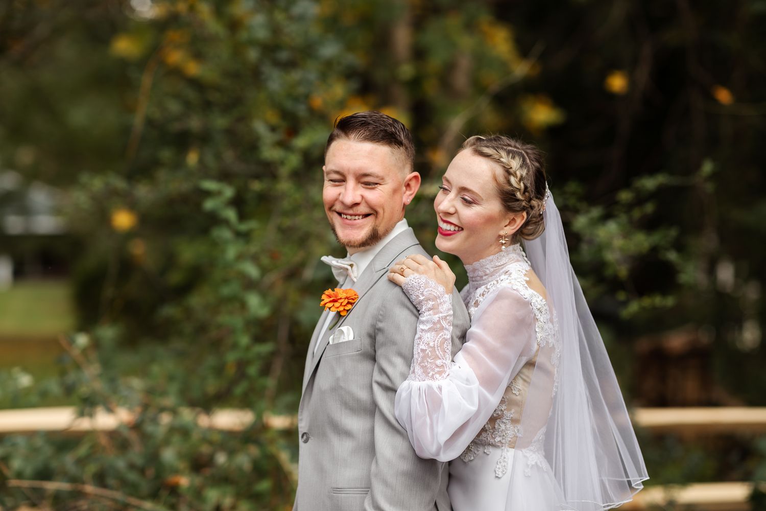 A joyful wedding couple shares an intimate moment together in an outdoor garden setting.