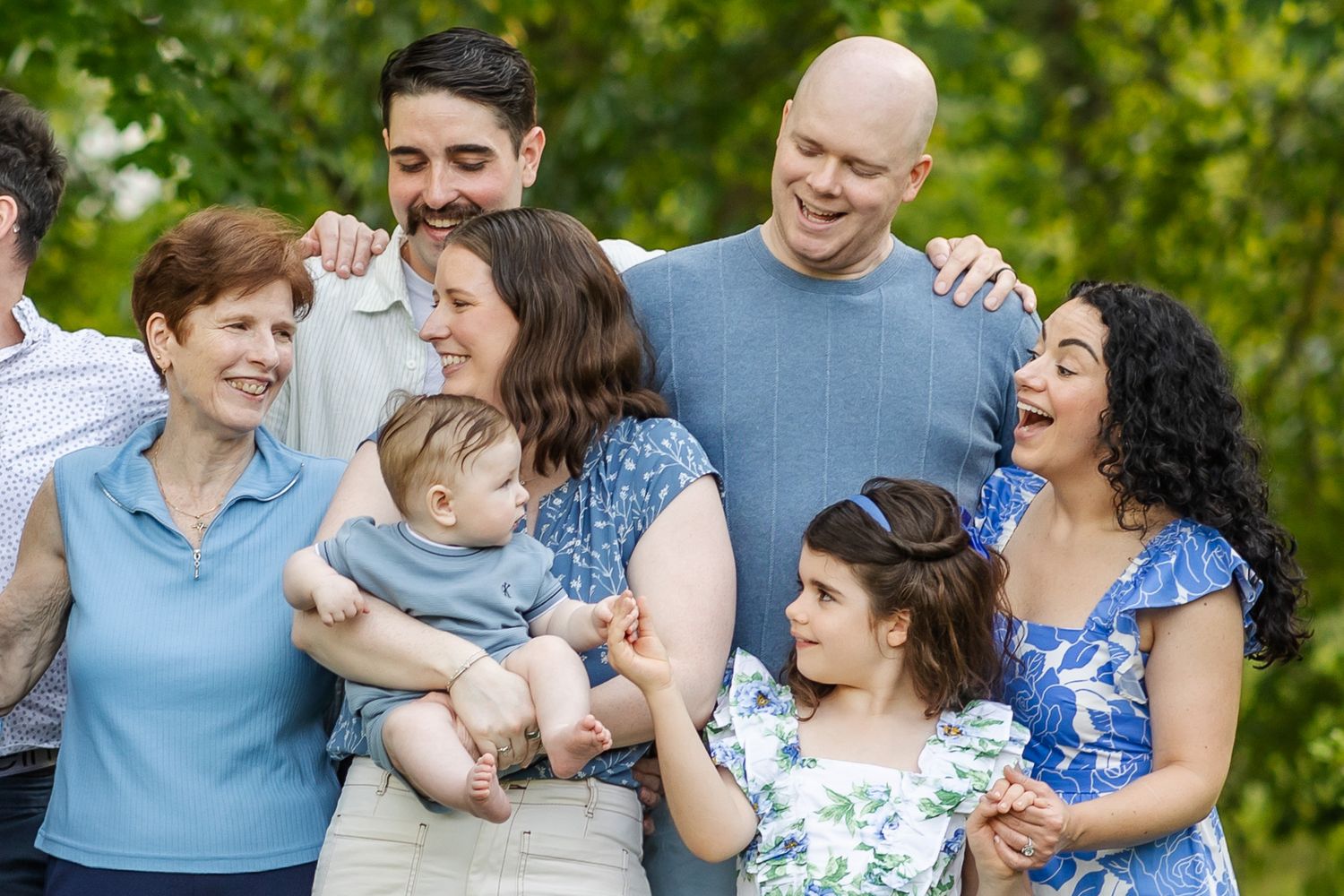 Happy multigenerational family smiling and laughing together outdoors in a lush green park setting.