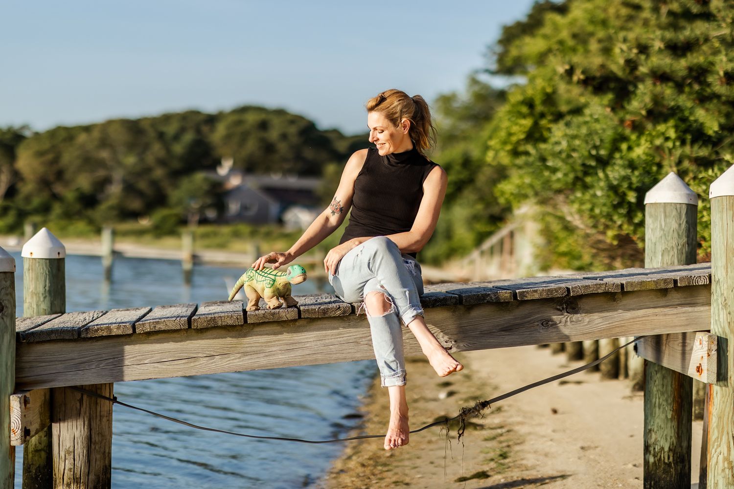 Researcher Kate Darling sits on the dock and smiles down at her pleo robot