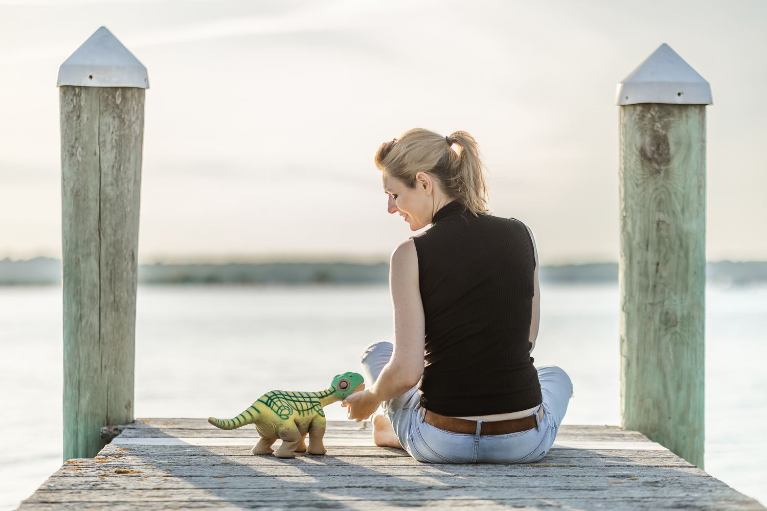 Robot ethicist Kate Darling sits on the dock with her small dinosaur robot