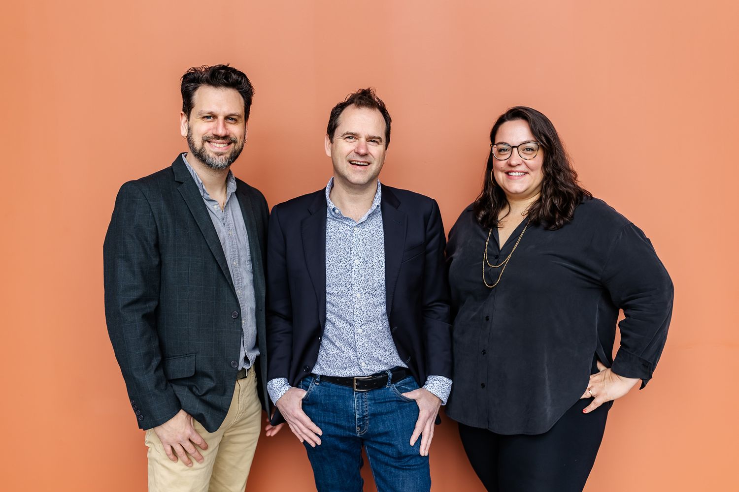 Realtor branding photo of three realtors standing against orange wall