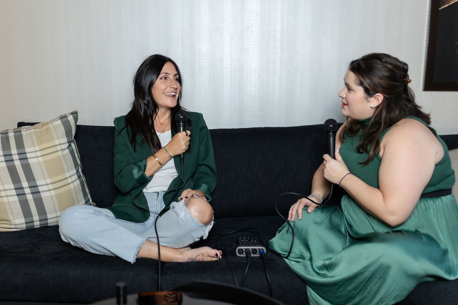 Two people in green loungewear sit on a couch having an animated conversation.