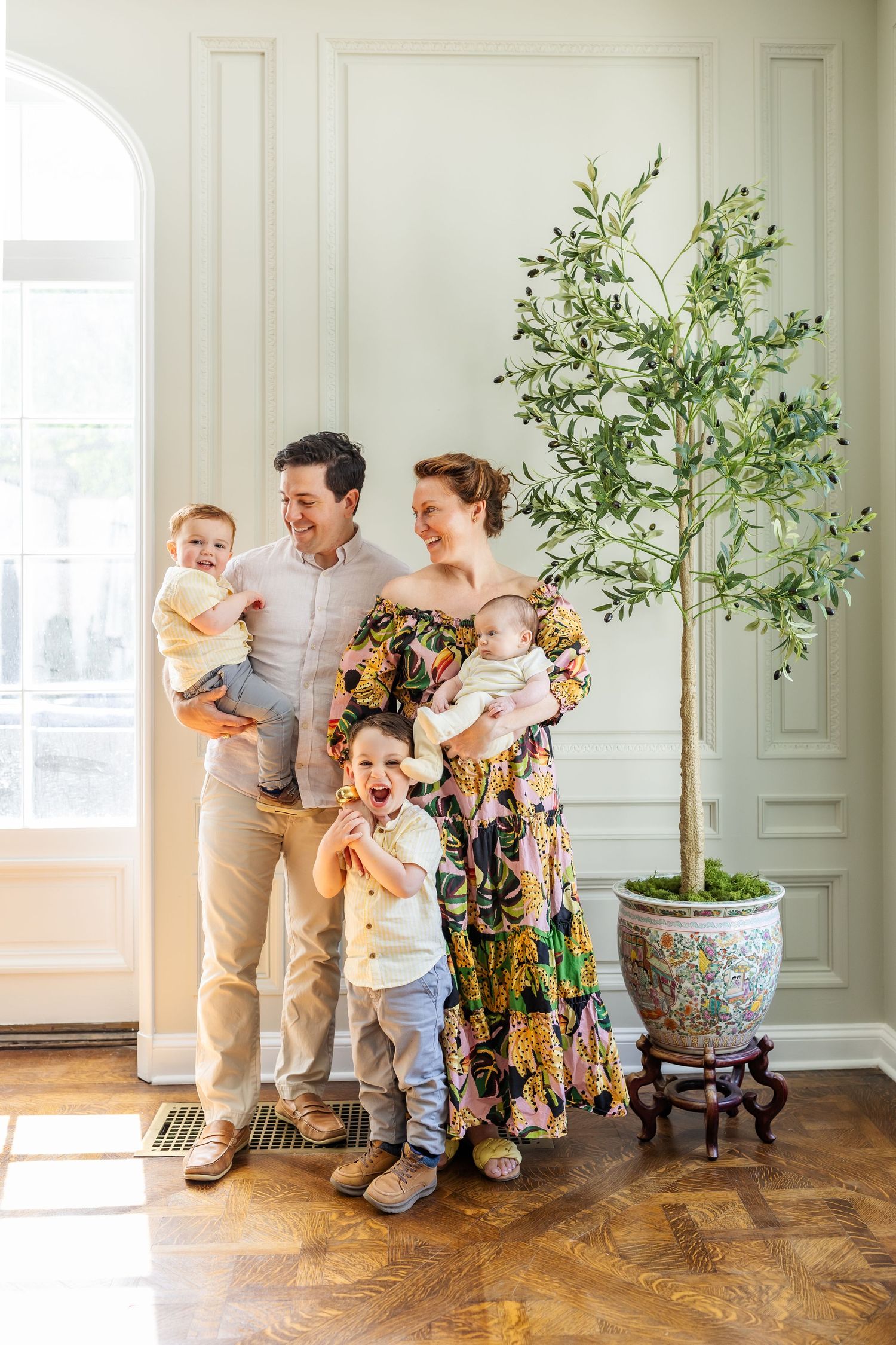 Bright indoor family photography session with greenery decor and natural lighting in an elegant room.