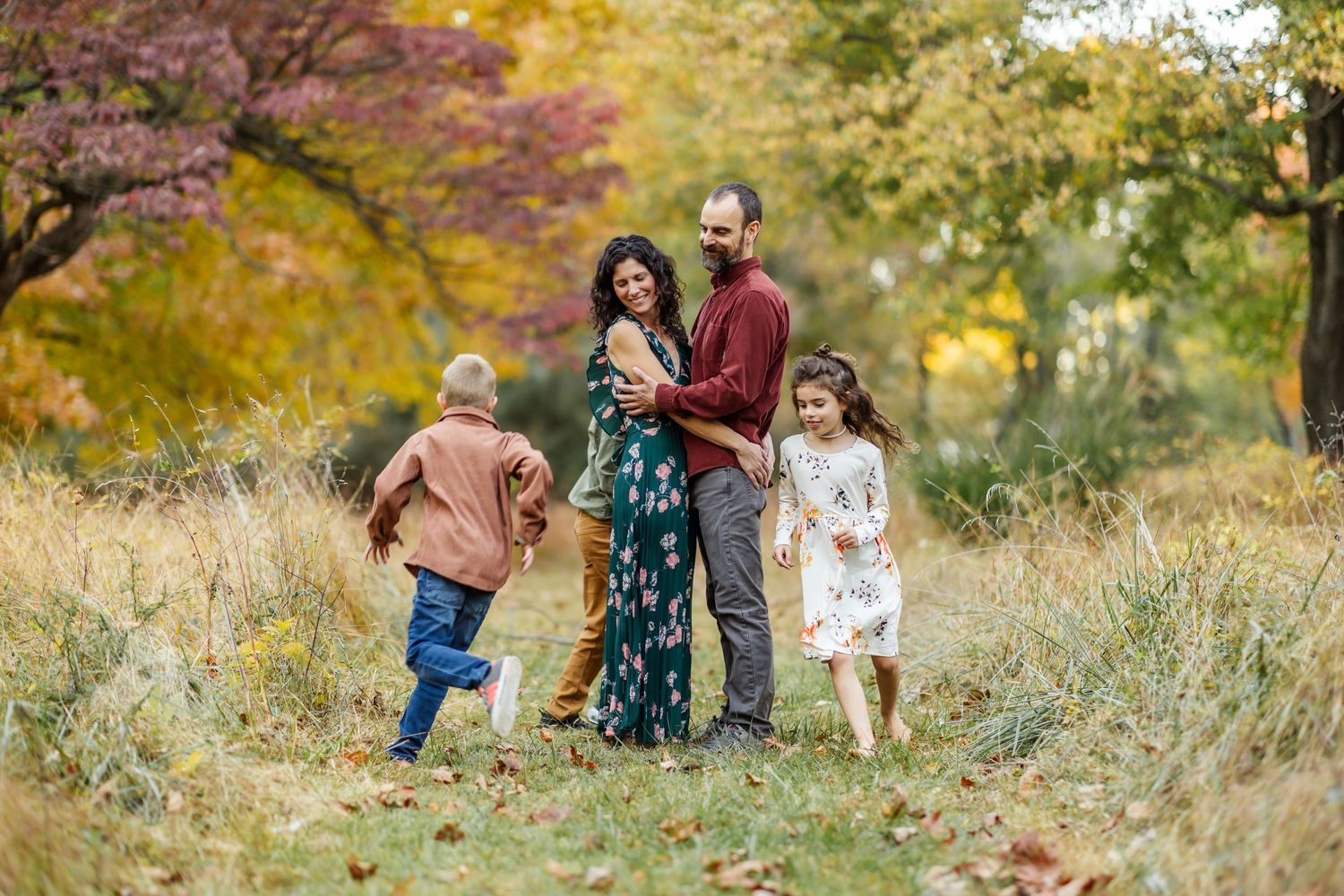 A family walking together through tall grass during golden hour in fall.
